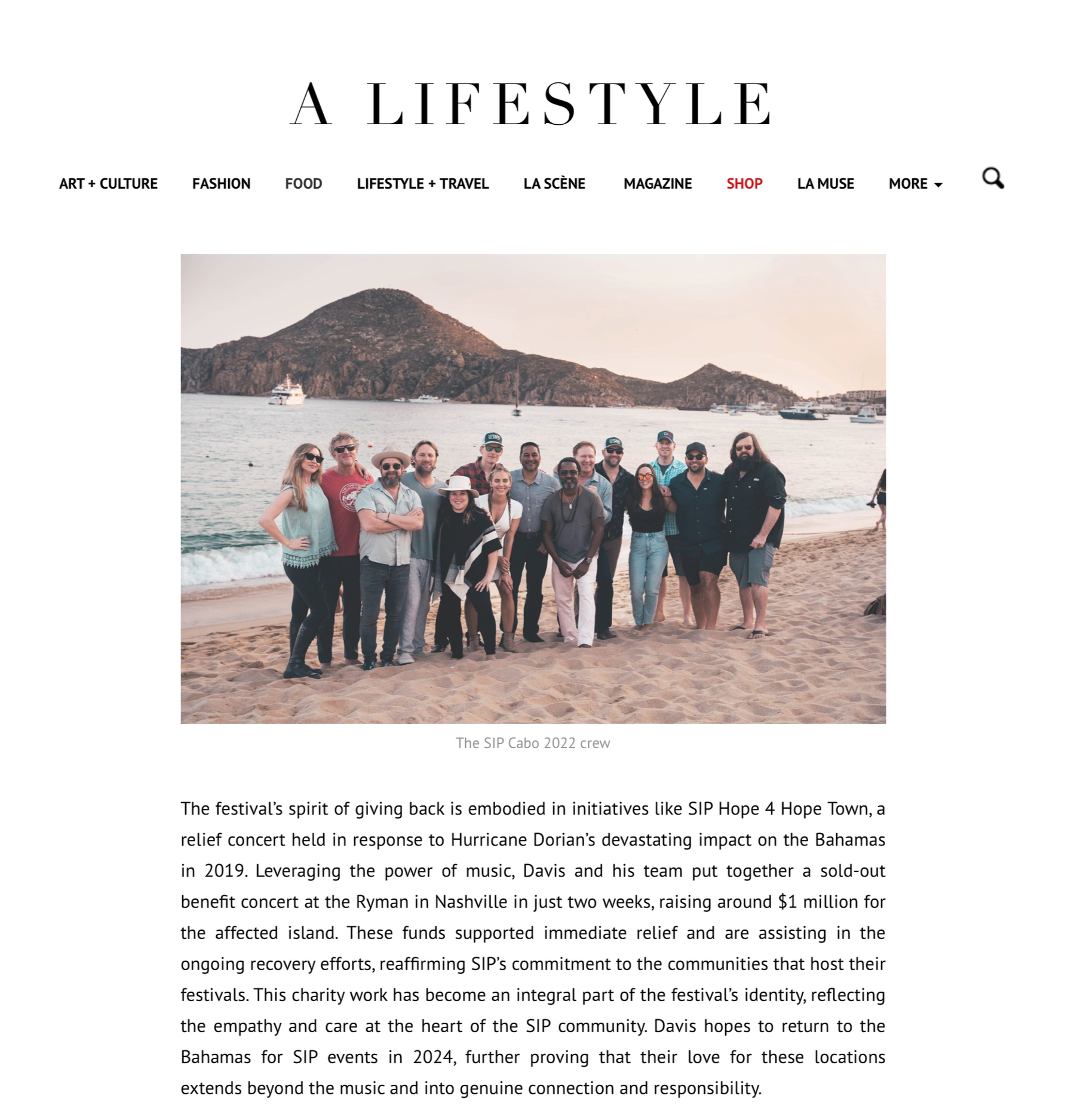 Group of people on a beach with mountains in the background, posing for a photo during sunset.