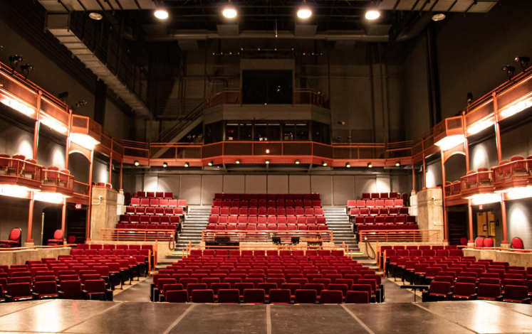 Interior of the PCC Proscenium Theater with red seats, balconies, and stage in the foreground.