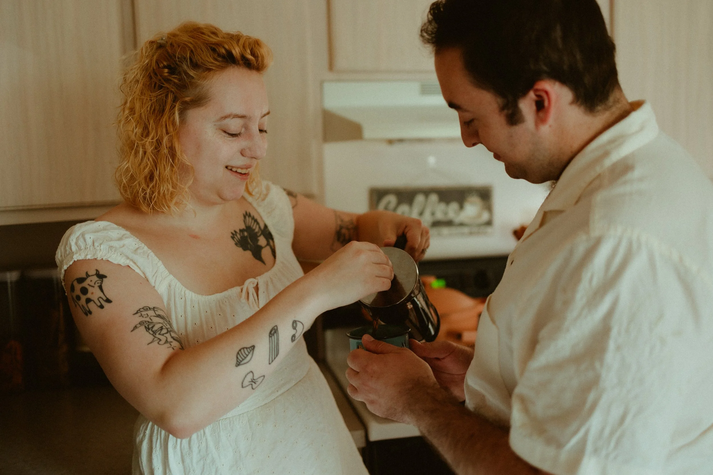 Engaged couple pour coffee for each other in their kitchen for this 'at home' couples photoshoot.