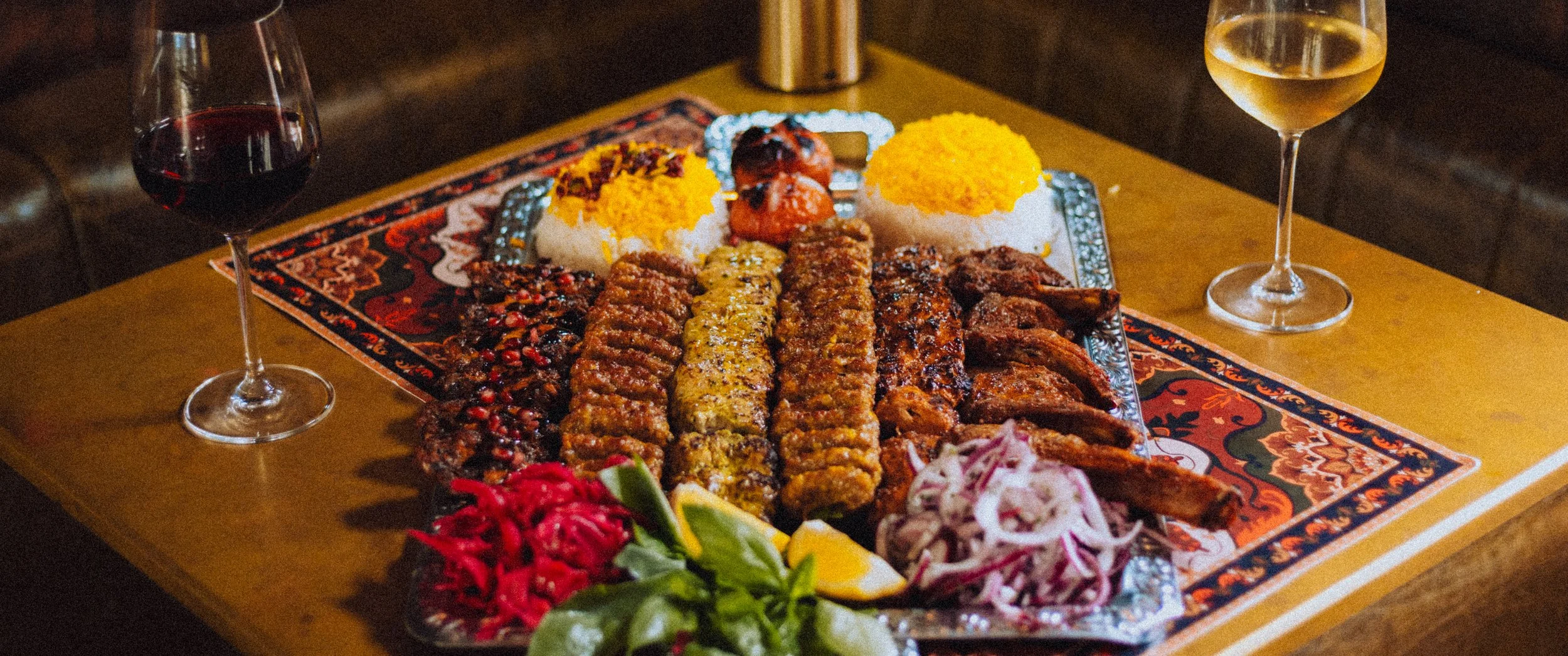 Baba’s Feast sharing platter with grilled lamb chops, jujeh kabab, koobideh kabab, and charred tomatoes at Baba’s Mezze.
