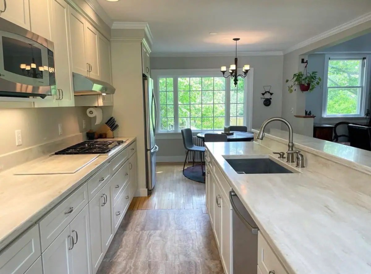 The kitchen at Baldwin Manor, white cabinetry and marble counters with an island