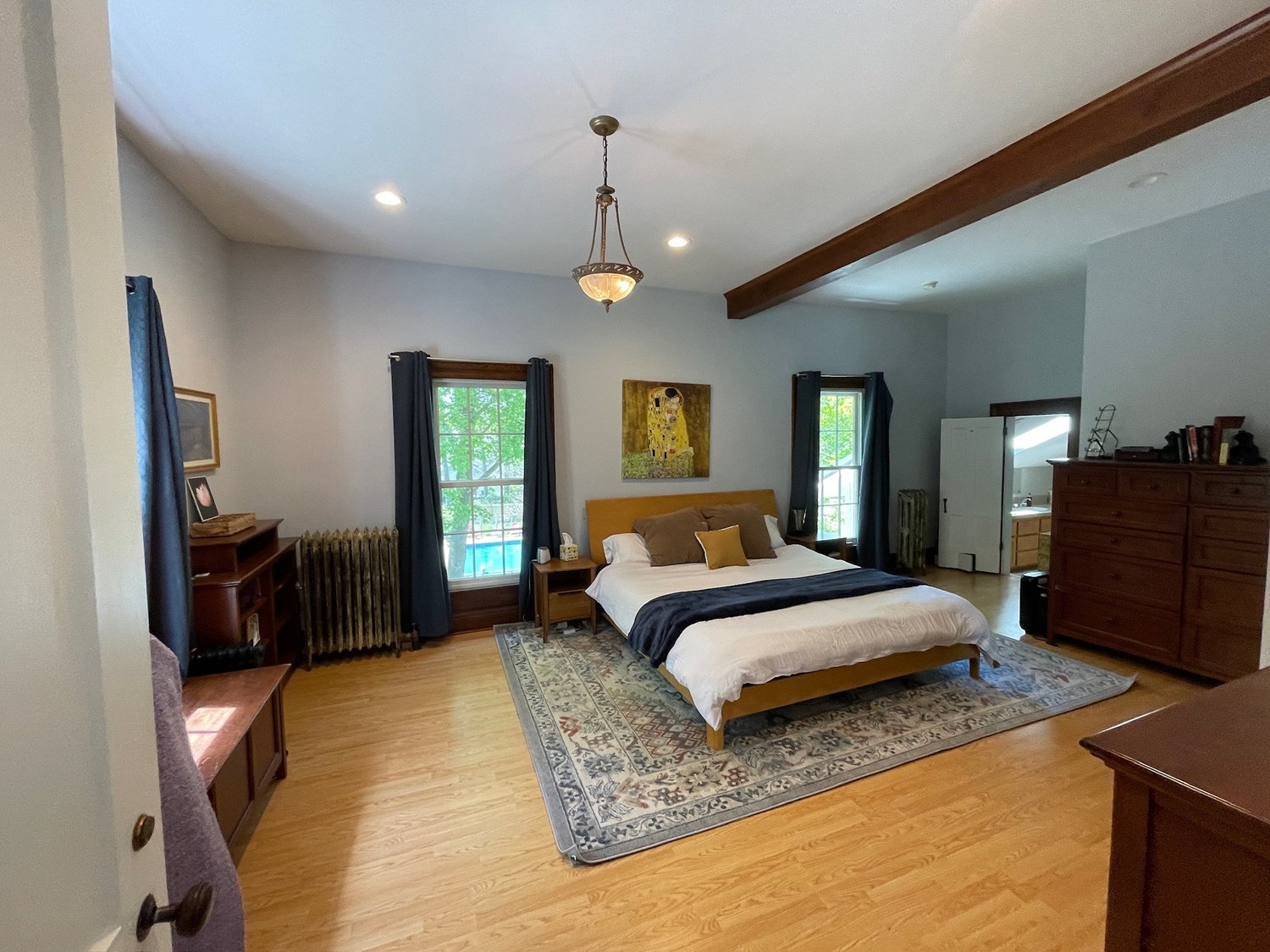A bedroom at Baldwin Manor with wood floors, chandelier and deep blue curtains