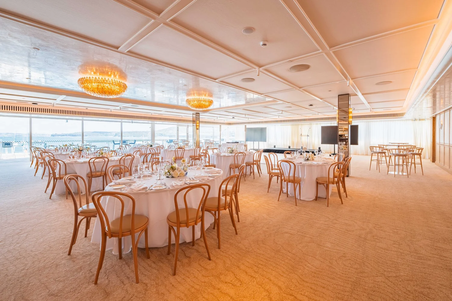 The Freshwater Room set with round tables and bentwood chairs under Murano glass chandeliers