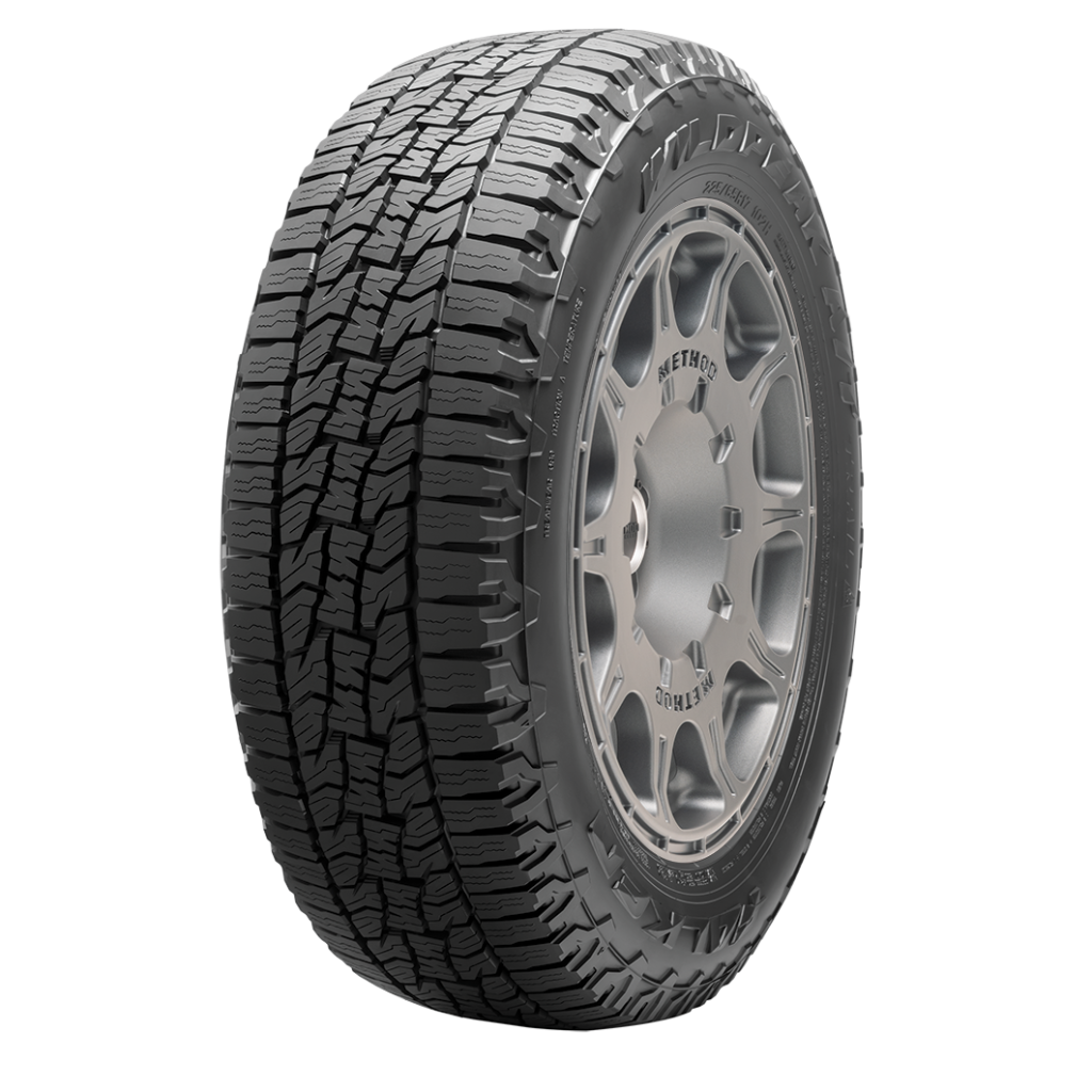 A close-up image of a black off-road vehicle tire with detailed tread pattern and a silver alloy rim.