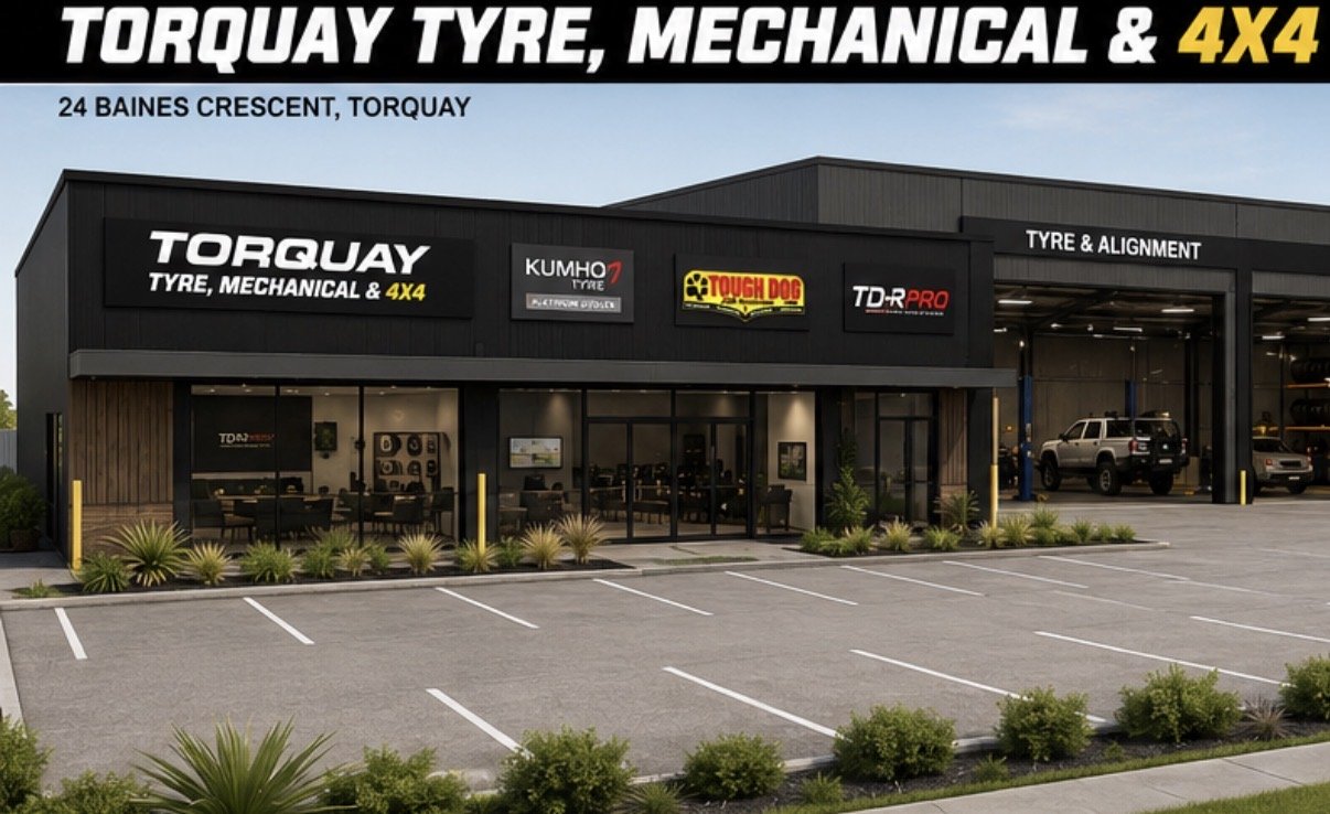 Exterior view of Torquay Tyre, Mechanical & 4X4 shop with multiple signs, including Kumho Tire, Tough Dog, and TDR Pro, with a parking lot in the foreground.