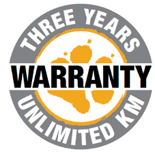 A circular badge with the text 'Three Years Warranty' and 'Unlimited KM' around the border. Inside, an orange sun setting over mountains with a black and yellow background.
