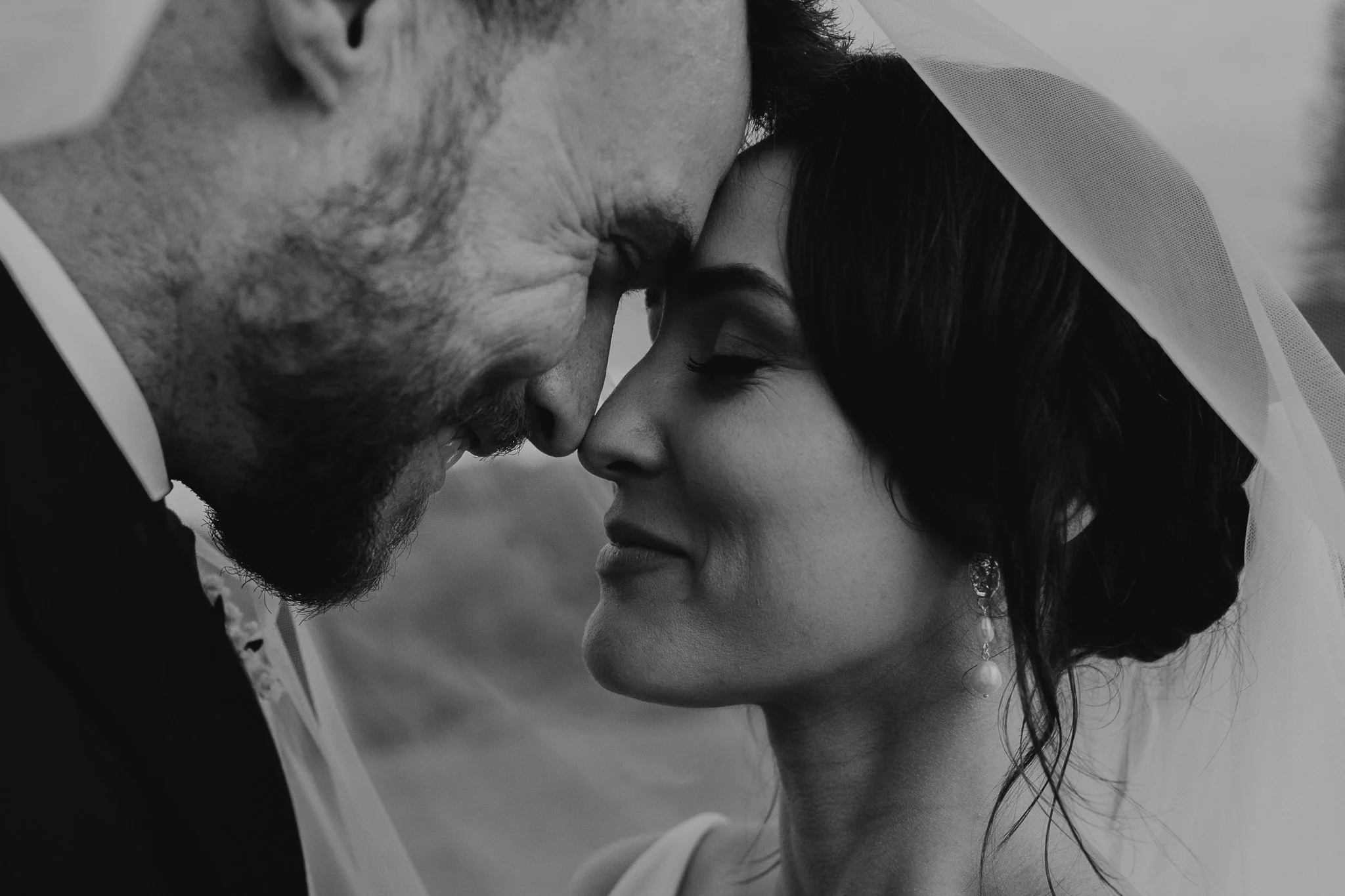 Close-up of a bride and groom with foreheads touching, their eyes closed, on a wedding day.