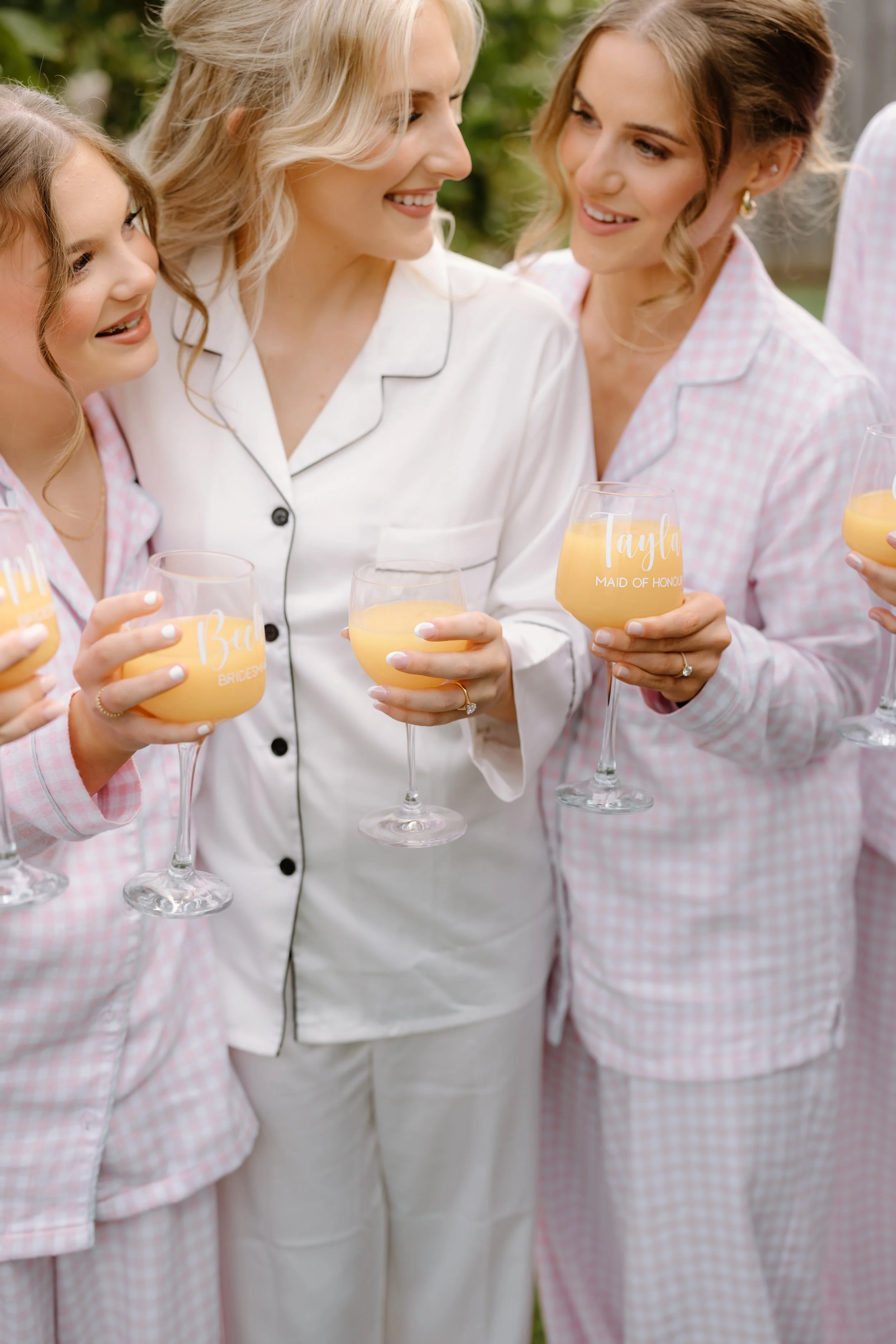 Women and girls in pajamas holding glasses with orange drinks at outdoor gathering.