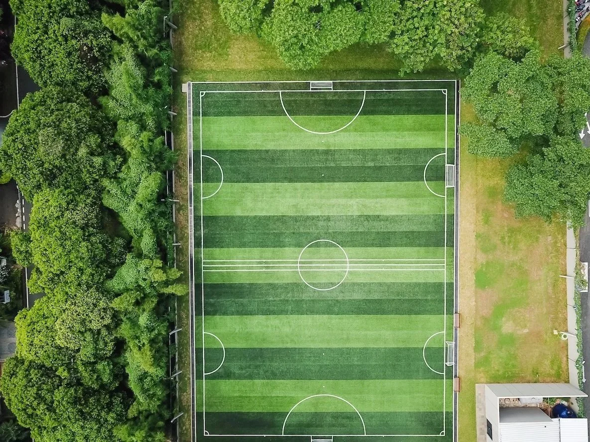 Aerial view of a soccer field at international school jakarta surrounded by trees and greenery.
