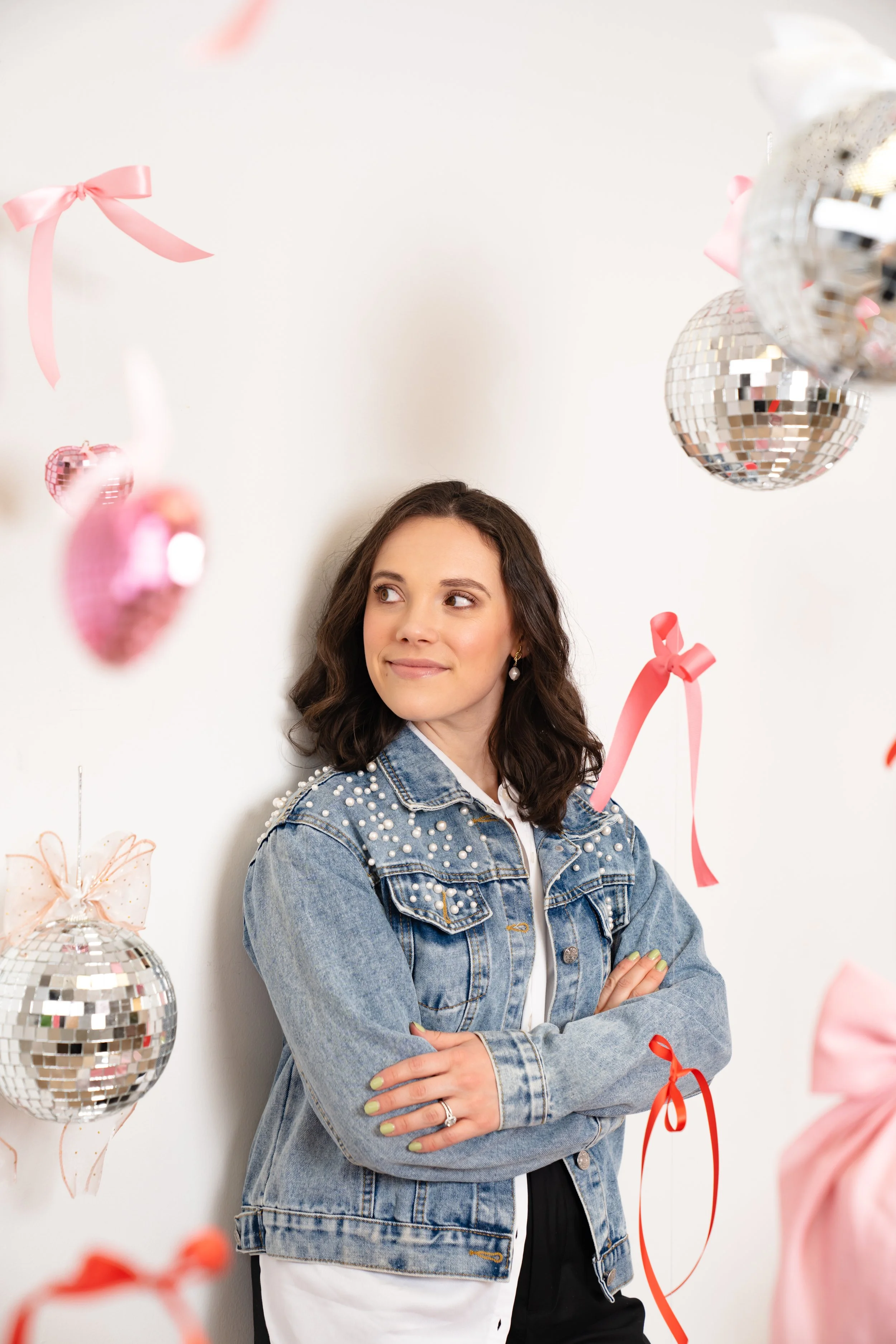 Karley founder of Bud to Bloom posing against wall with ribbons and disco balls hanging from ceiling