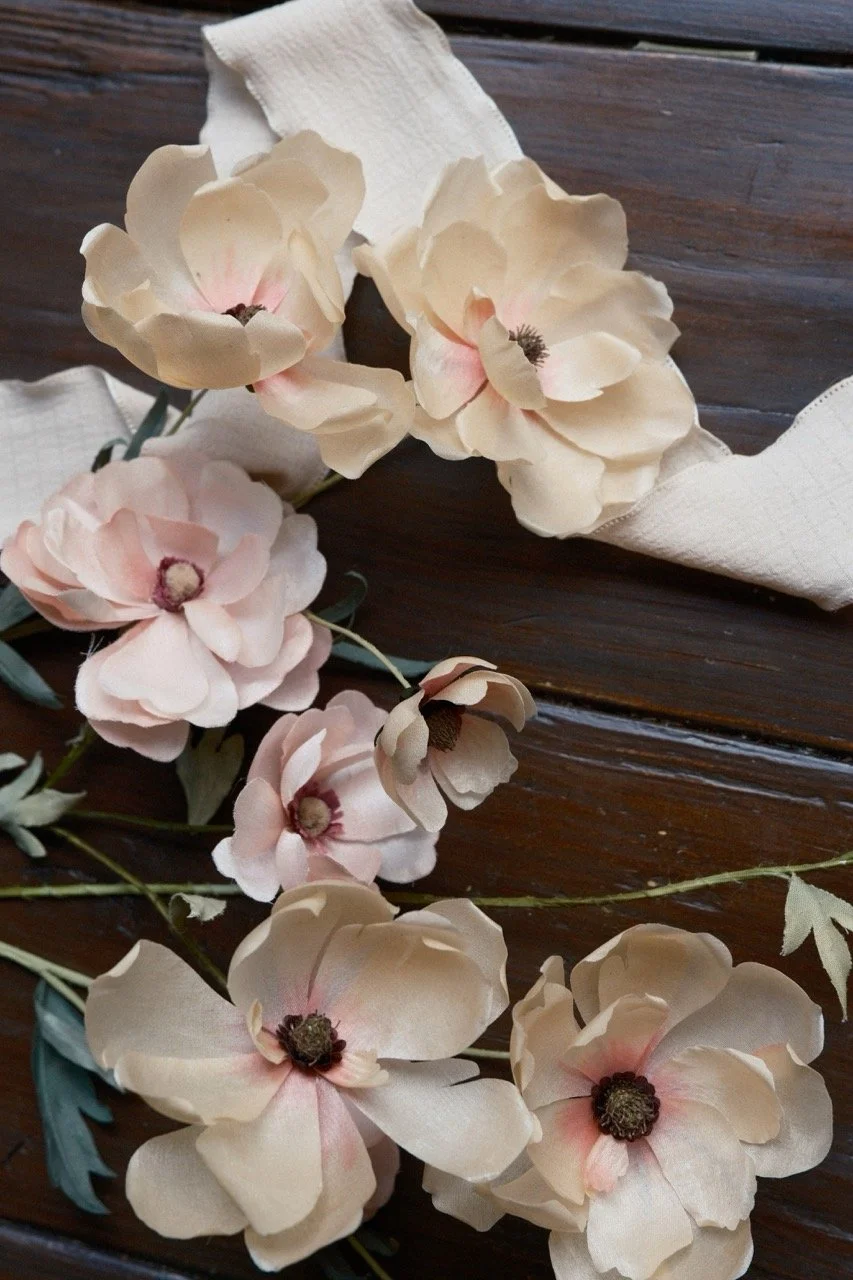 Cream-colored artificial flowers with dark centers arranged on a dark wooden surface.
