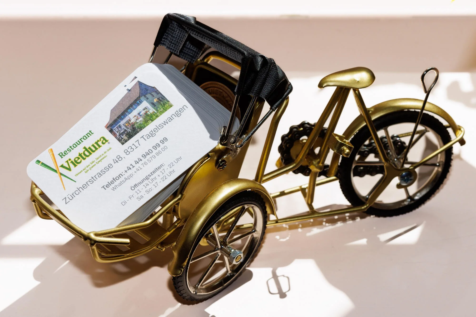 Vietnamesisches Miniaturfahrrad mit einer Visitenkarte im Korb. Die Visitenkarte Restaurant Vietdura in Tagelswangen