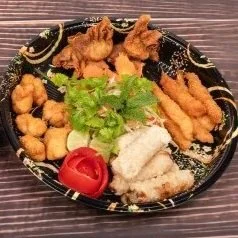 Verschiedene fritierte Speisen, Salat, Tomate und Reis auf einem schwarzen Teller