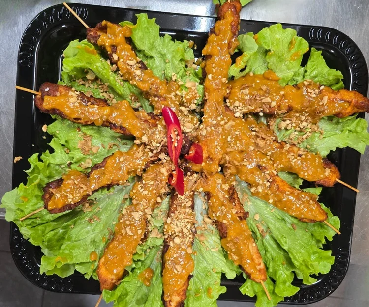 Poulet-Spiesse an hausgemachter Satay-Sauce mit gehackten Erdnüssen, sternförmig angerichtet.