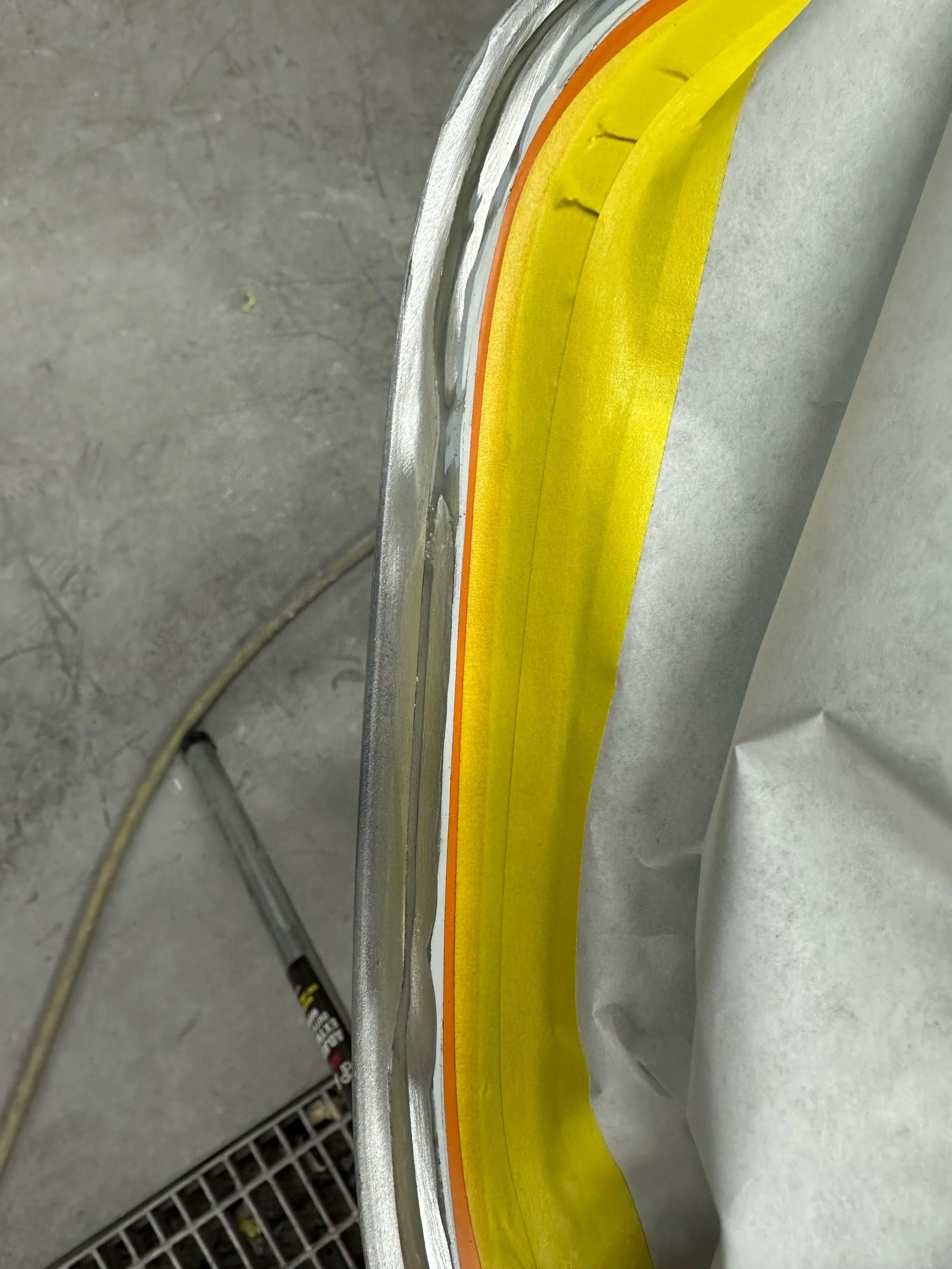 Close-up of vehicle bodywork with masking tape and protective paper used for painting.