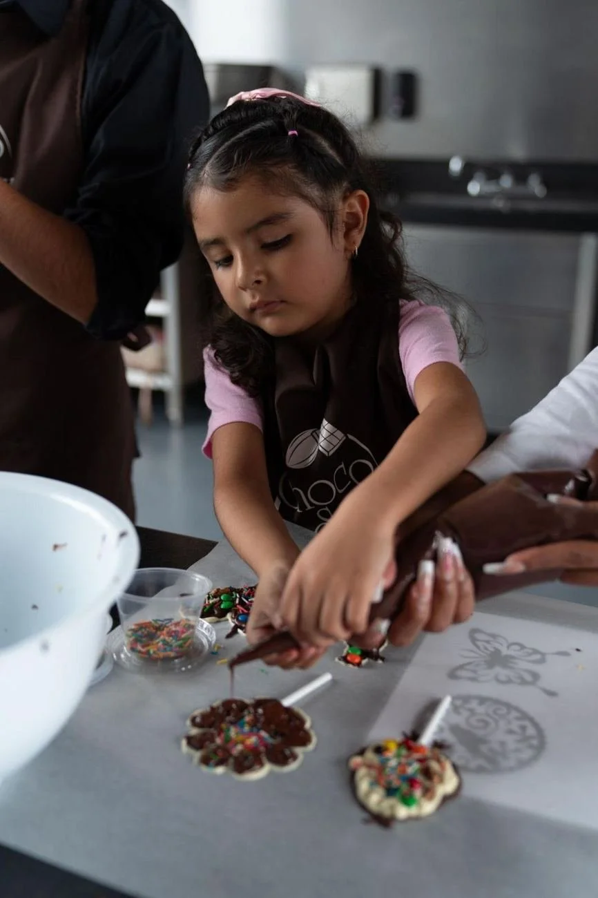 Niña decorando sus paletas de chocolate en el taller de cumpleaños