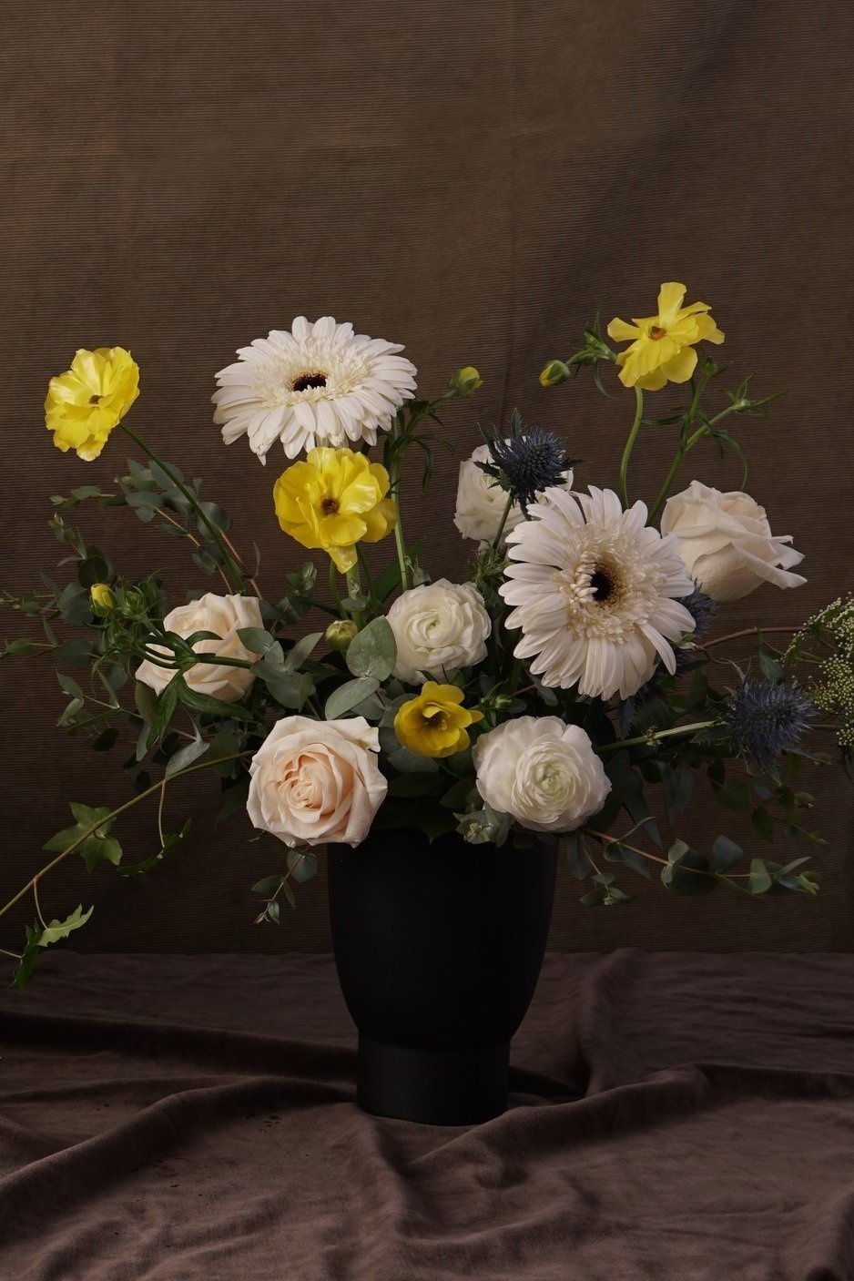arrangement funéraire de fleurs blanches, jaunes et vertes.