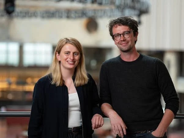 Smiling woman and man posing together in a modern office or studio.