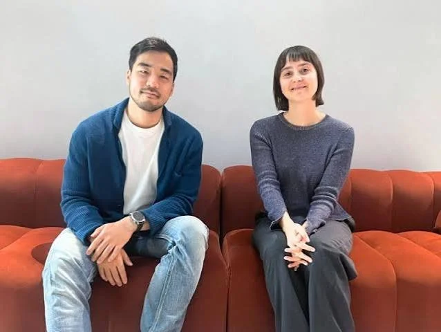 Man and woman sitting on a red couch and smiling at the camera