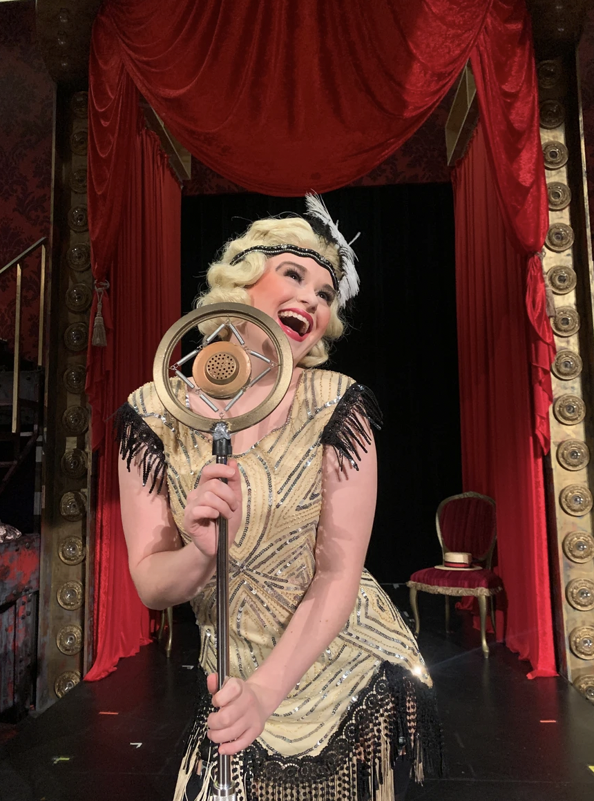 A young female performer posing with a microphone