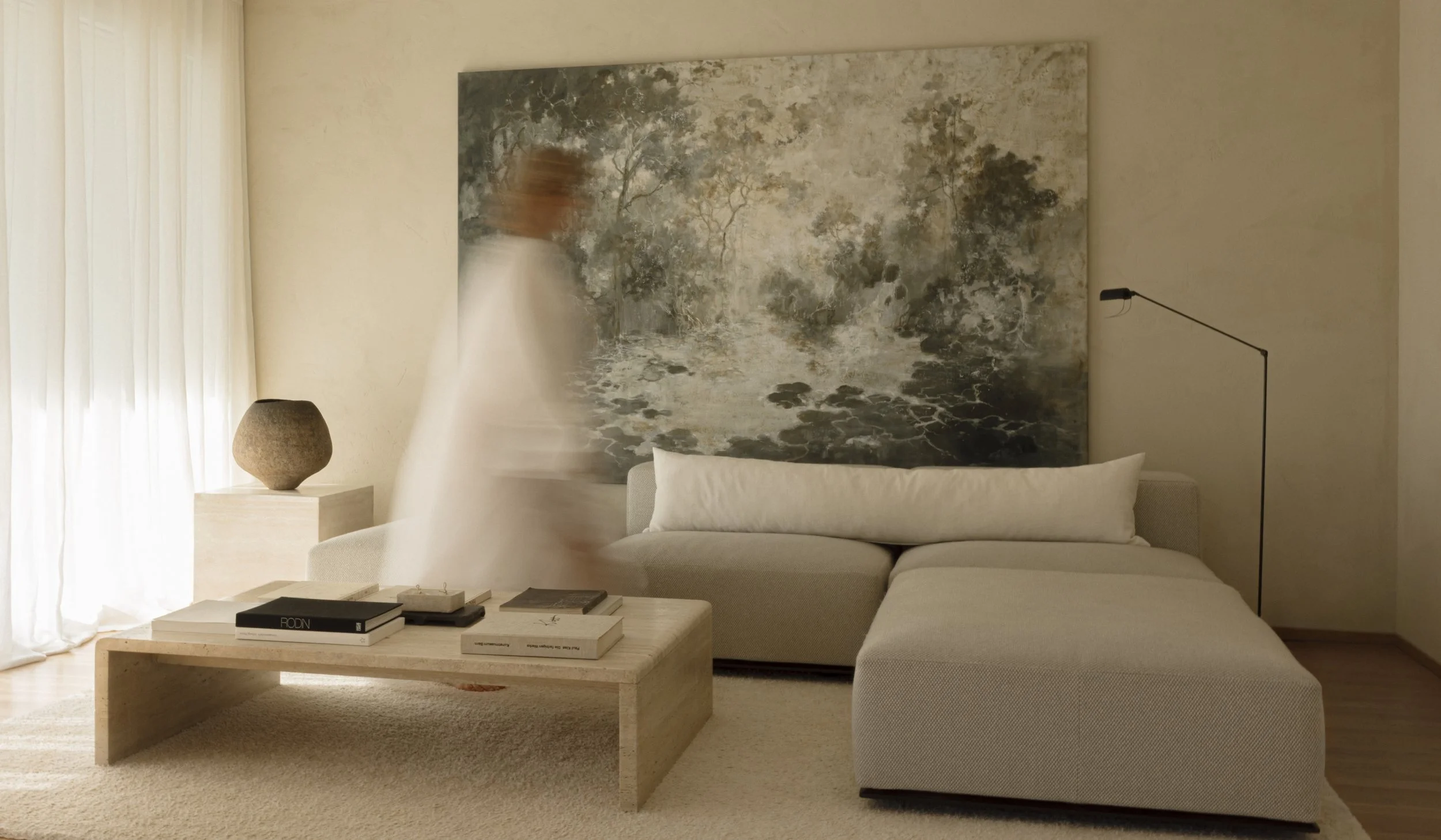 An ethereal interior scene with a blurred figure in white, showcasing the "Art of Living in Calm" concept with neutral tones and soft natural light.