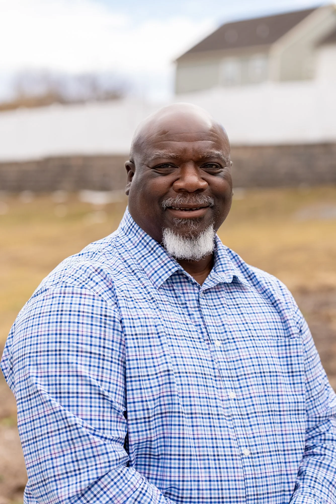 a man smiling wearing a blue and red striped shirt