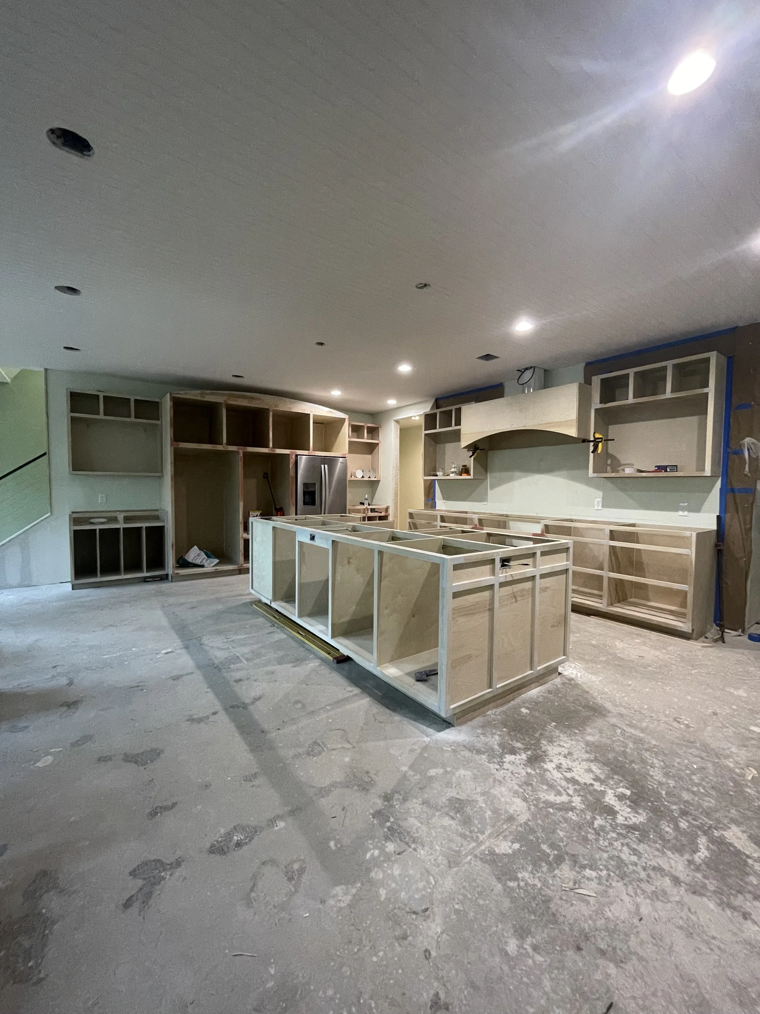 Kitchen under construction with wooden cabinets and an island frame in progress.