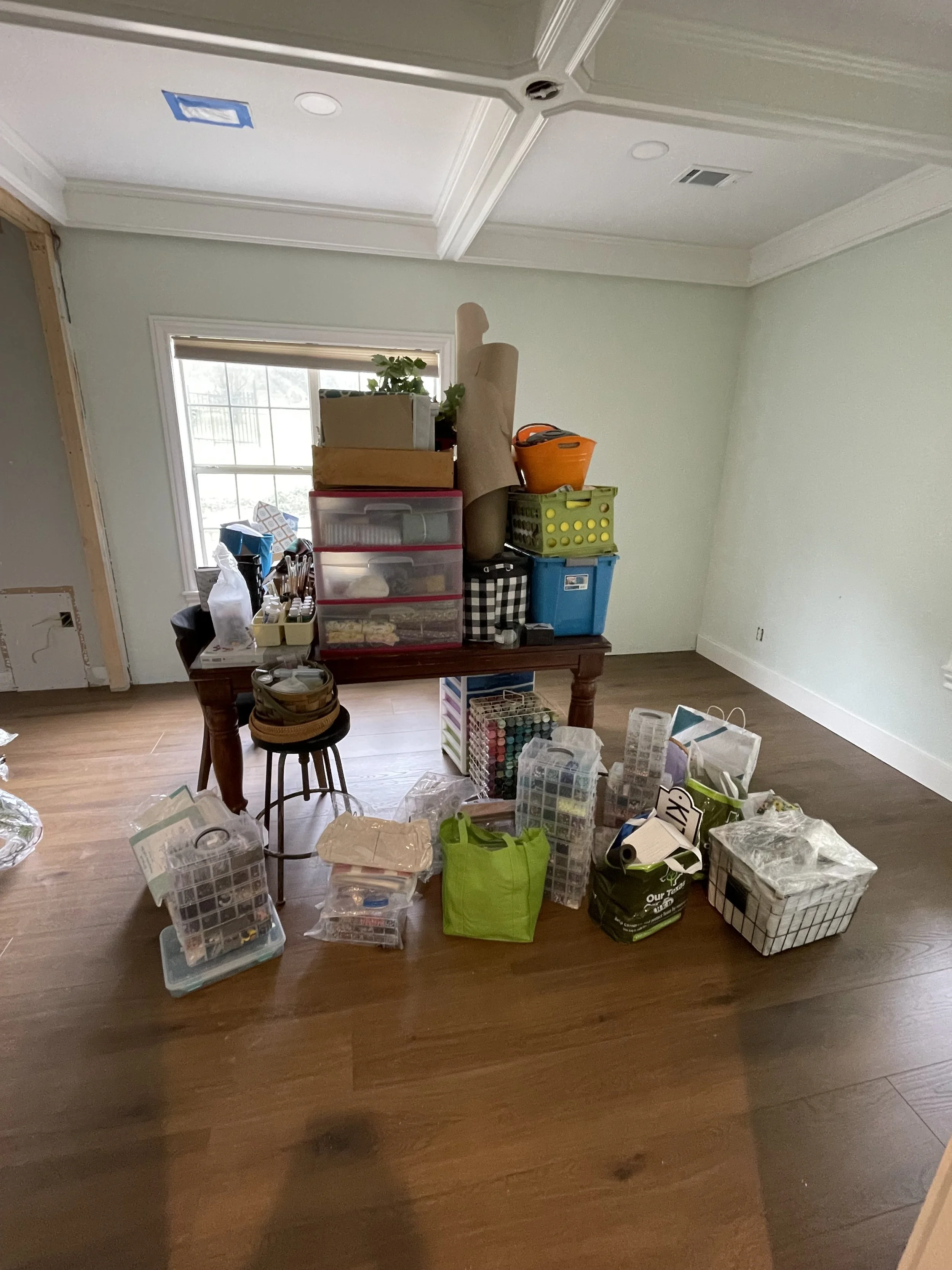Room filled with craft supplies, storage boxes, and a mannequin on a table near a window.