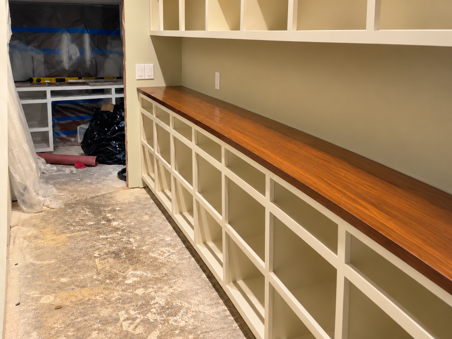 Custom built-in wall shelving and cabinetry with a dark wood countertop under construction