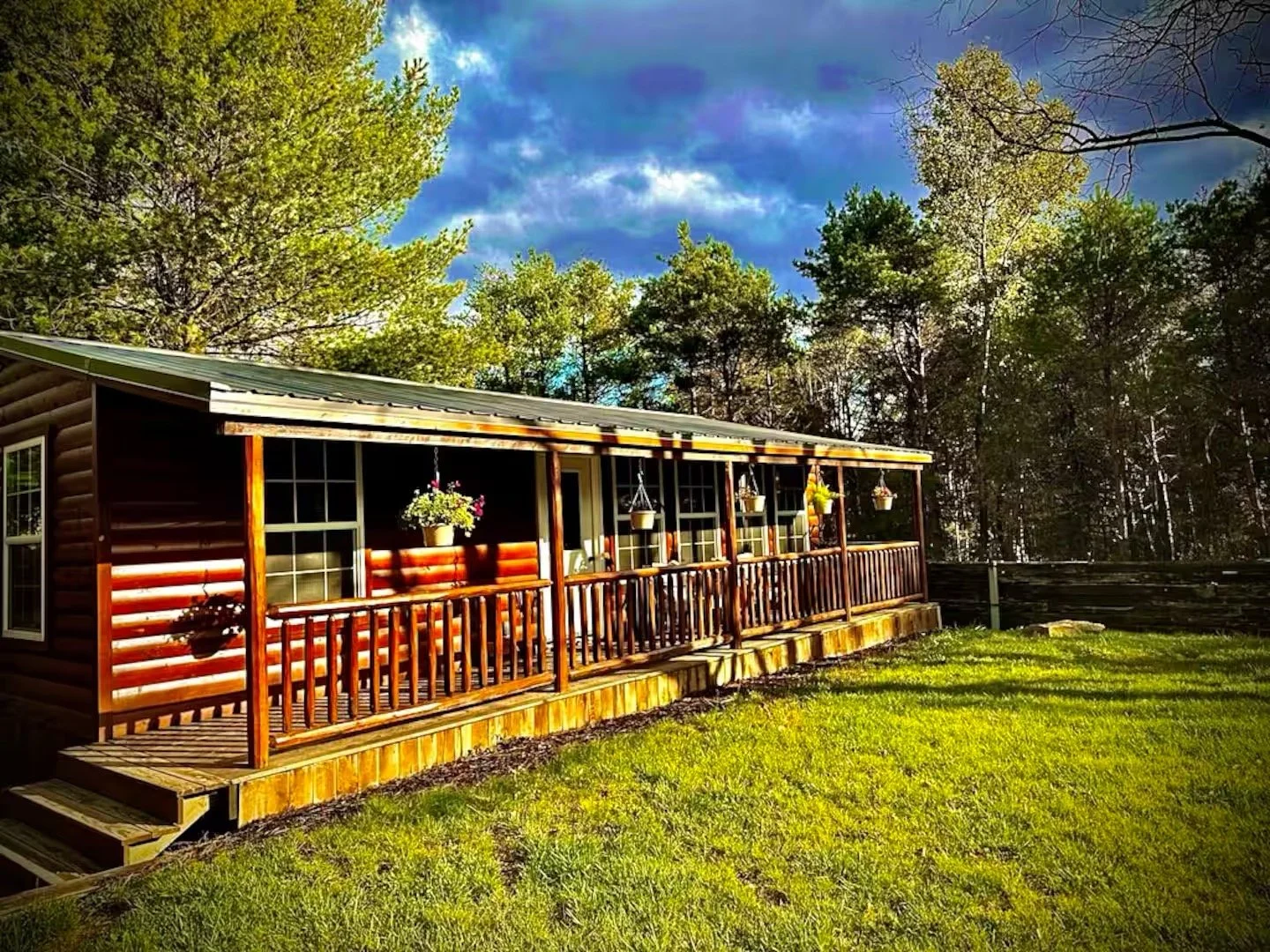 Forest Villas cabin with a covered wraparound porch on the wooded grounds in Marienville, Pennsylvania