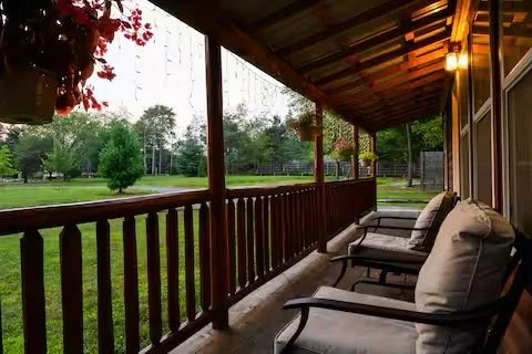 Covered cabin porch with lounge chairs looking out over the lawn at Forest Villas