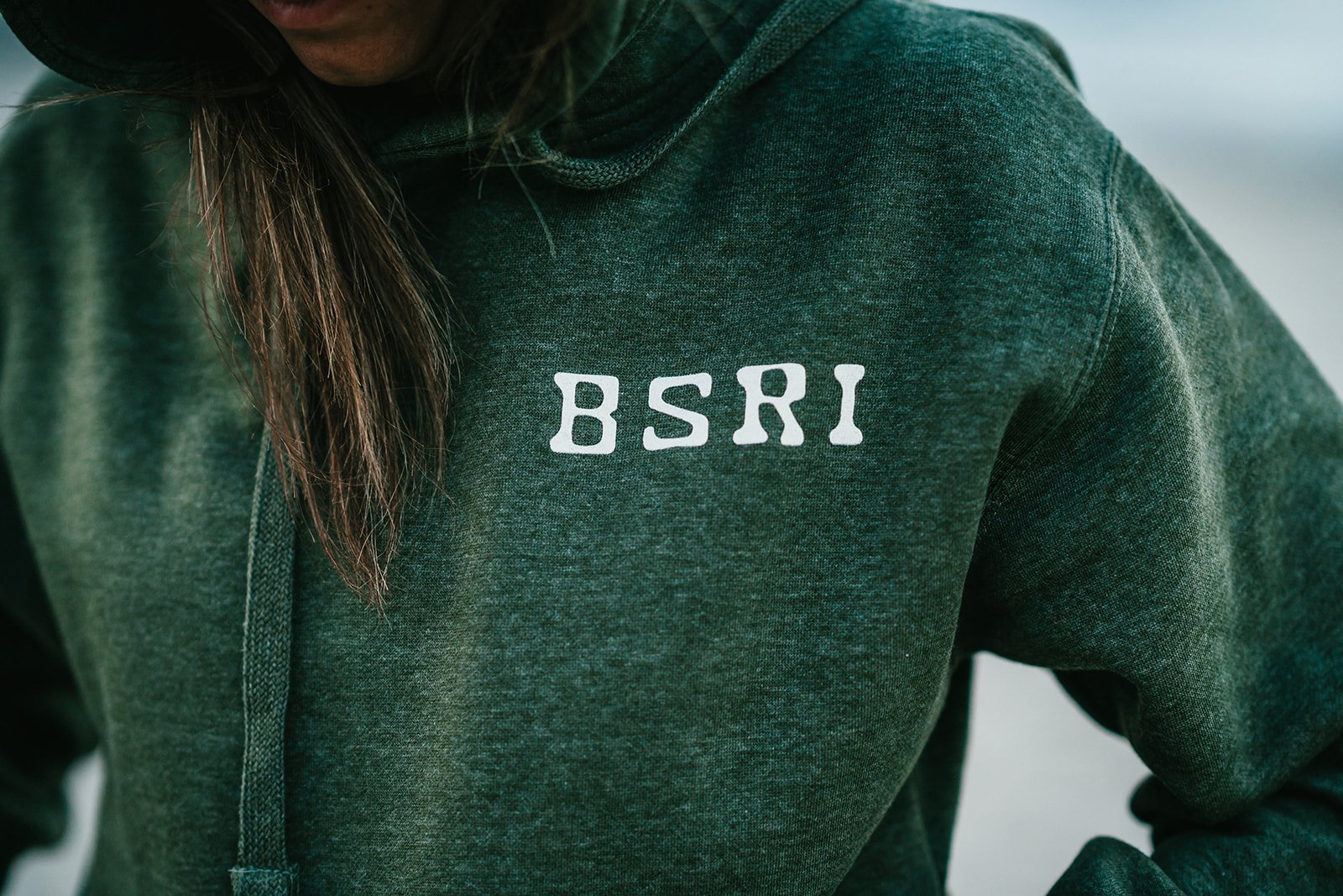 BigSurRiverInn-BigSur-GeneralStore-BSRILogo-Sweatshirt-Green-Front-Female-FullView-Angled-Moody-PfeifferBeach-HannahOvereemPhoto.jpeg