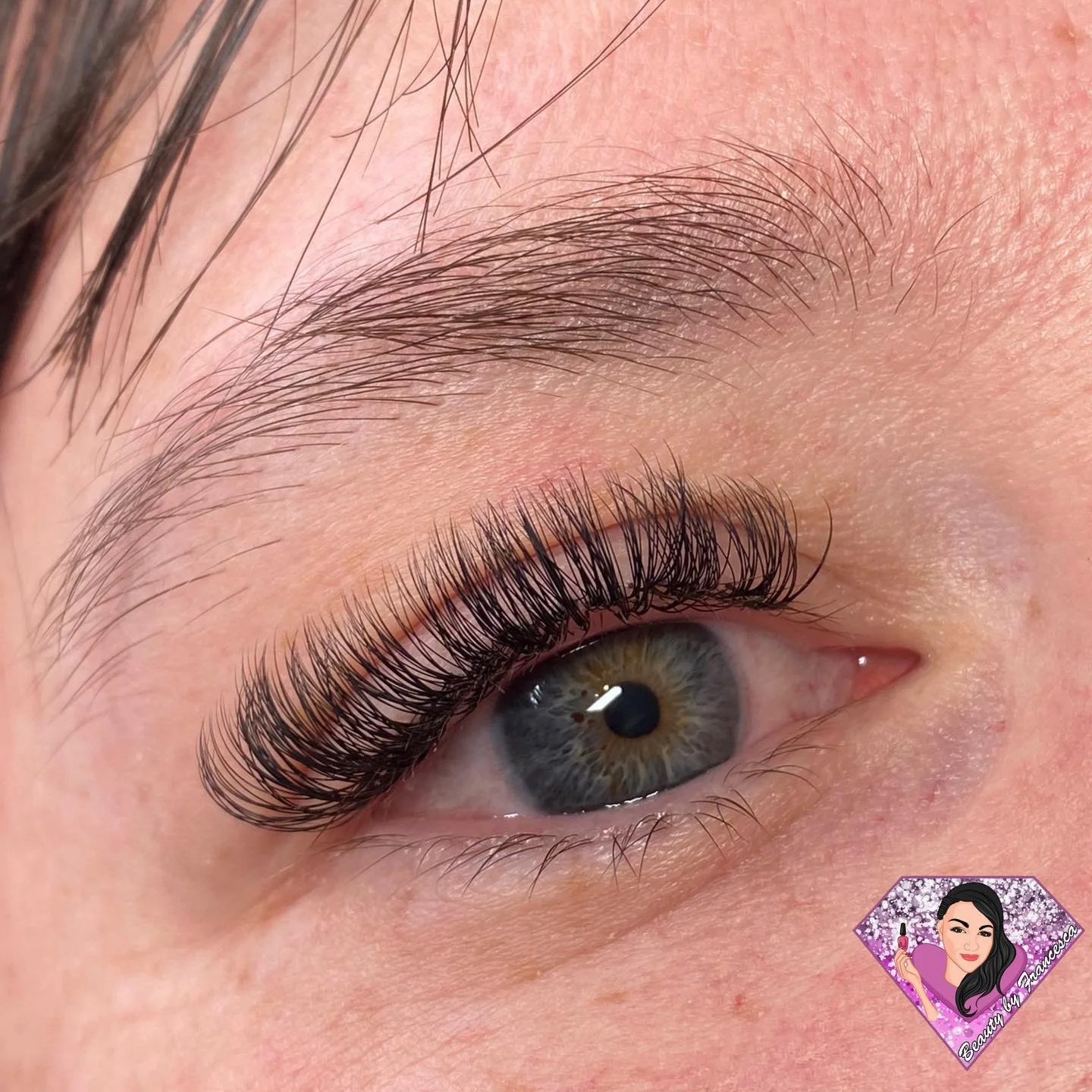 Close-up of a woman's eye with long, curled eyelashes and well-groomed eyebrow.