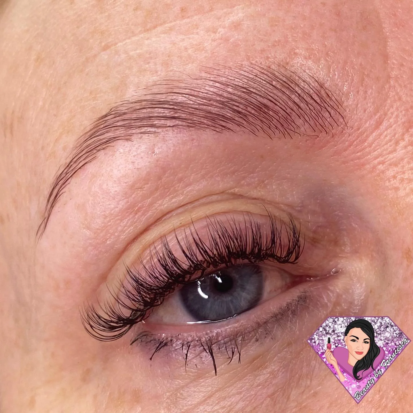 Close-up of a person's eye with long, curled eyelashes and well-groomed eyebrows.