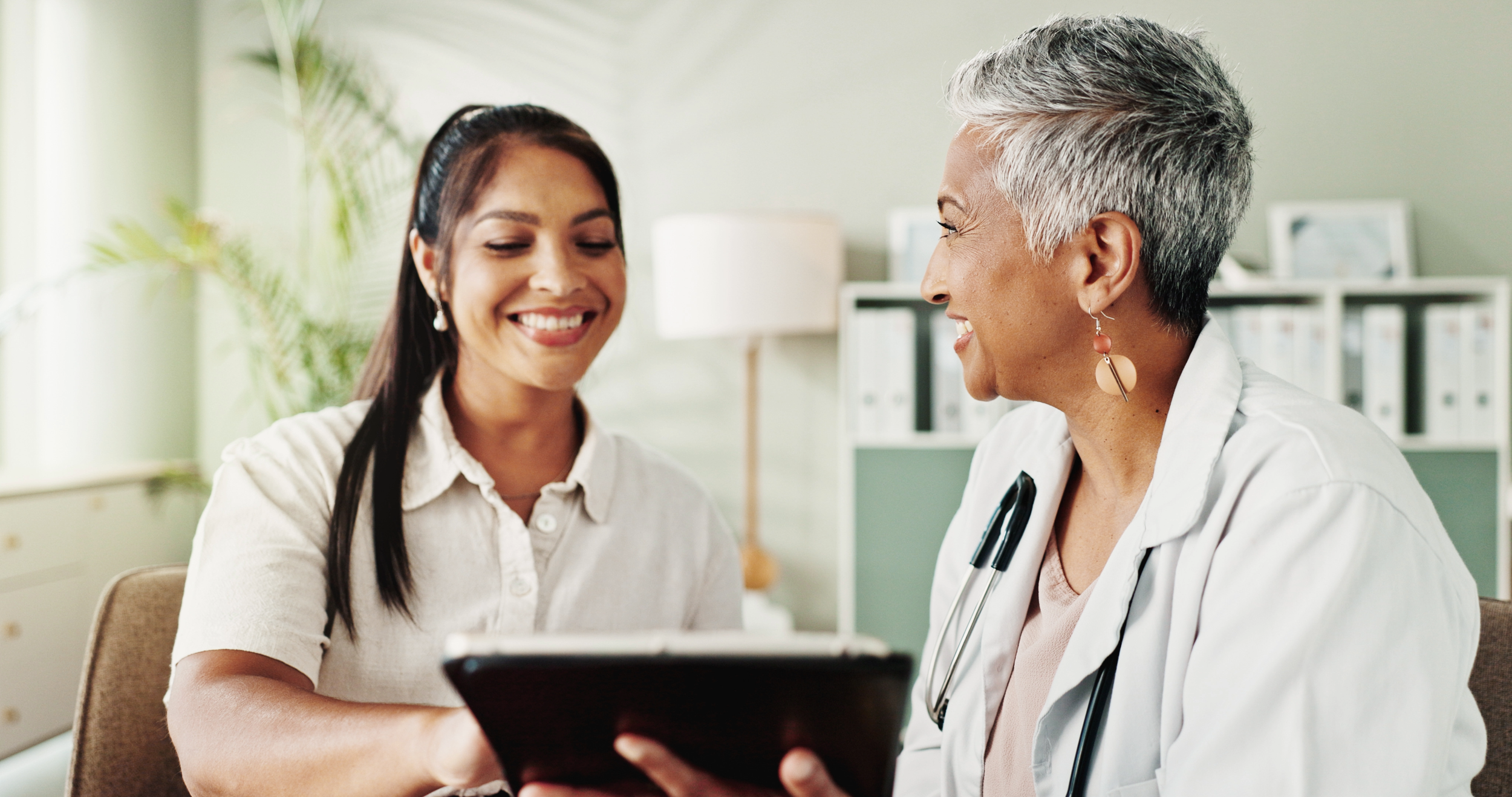 A healthcare professional speaking with a smiling female patient in a bright, modern office.