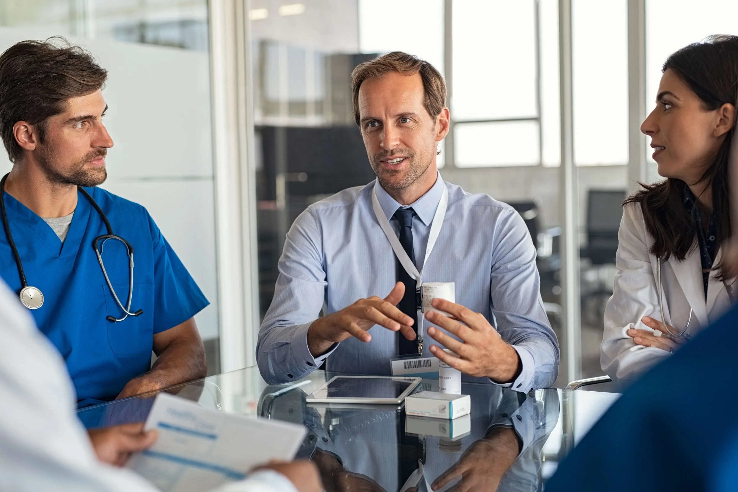 Medical team meeting with a doctor discussing medication in a hospital conference room.