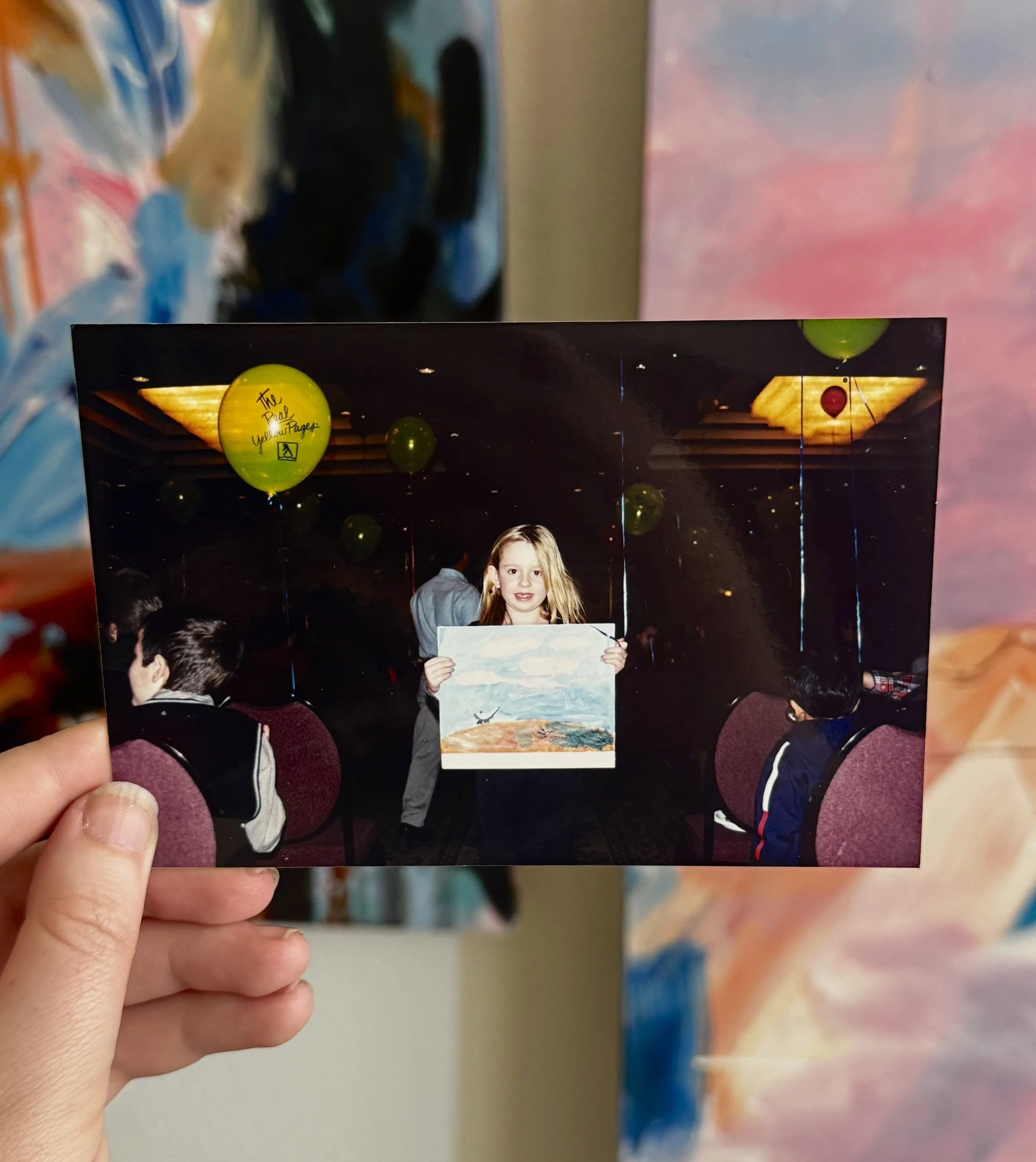 holding a photo of a young girl at her first art show