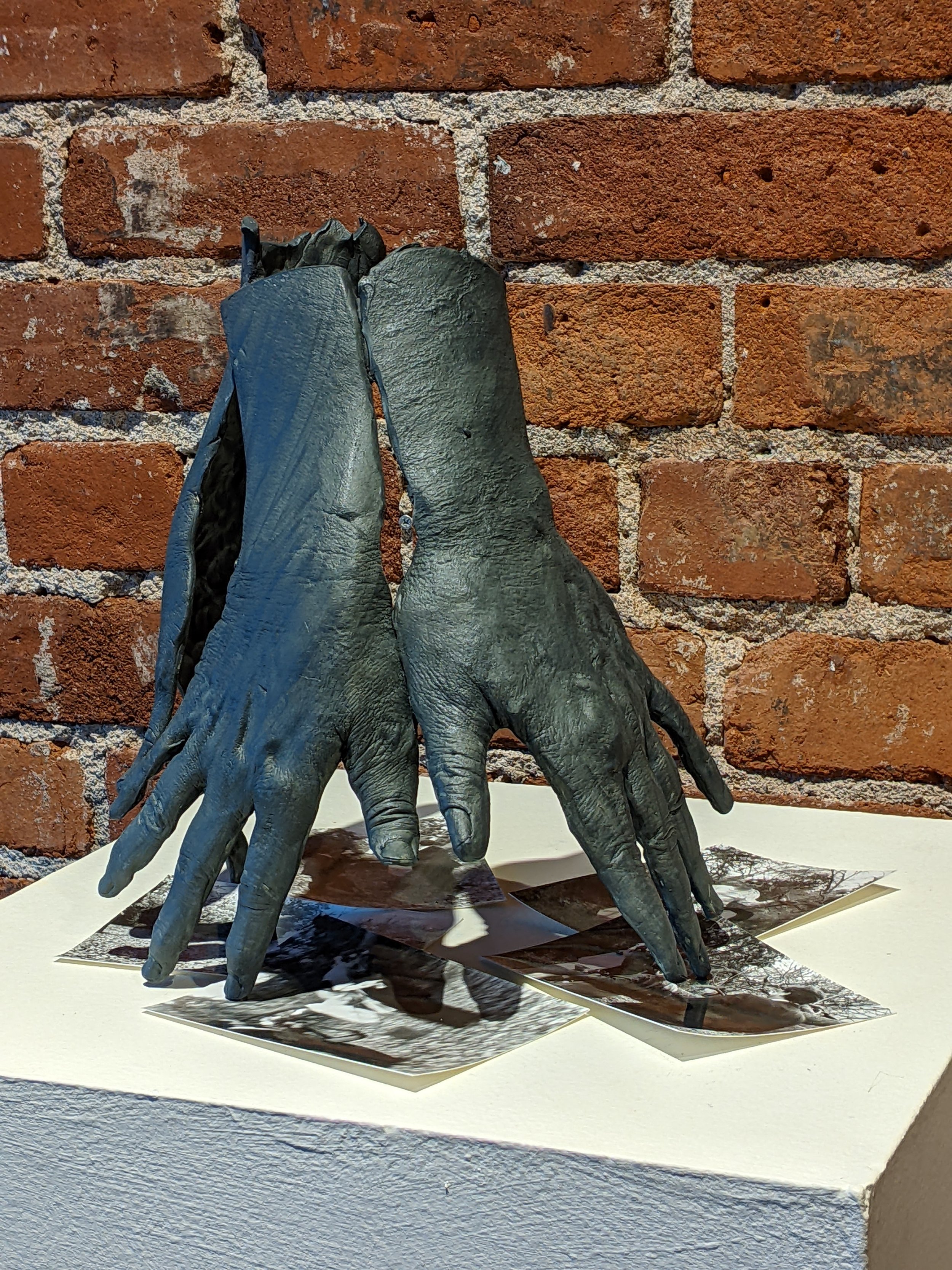 Standing ceramic hands pinning old family photos from Lost & Found show 2024