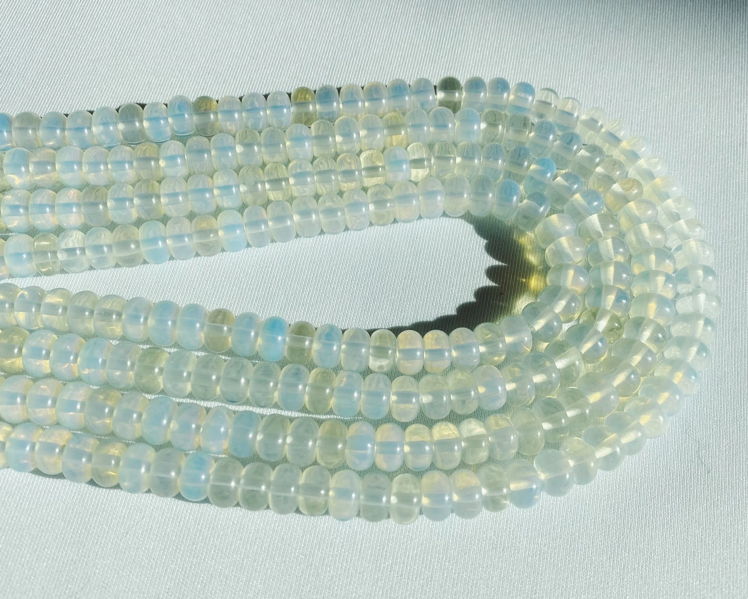 Close-up of multiple strands of iridescent white pearls on a white textured surface.