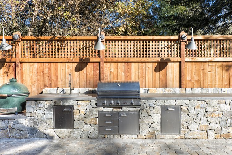  An outdoor kitchen with appliances built into a stone countertop.  