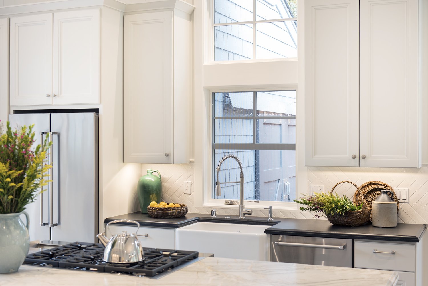  A sink with silver fixtures in front of a tall window.  