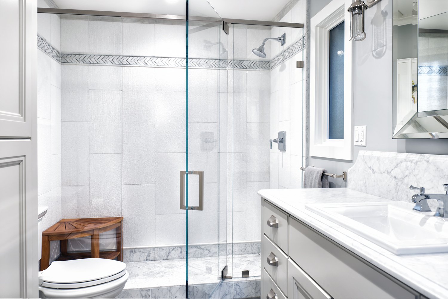  A large glasses in shower with decorative tile.  