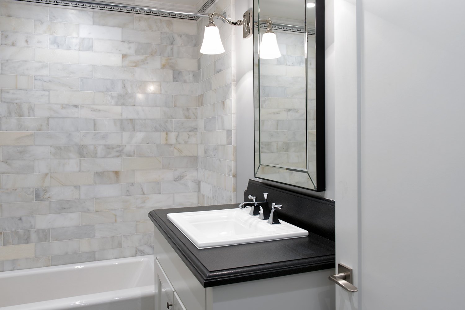  Bathroom vanity with a black countertop and silver fixtures.  