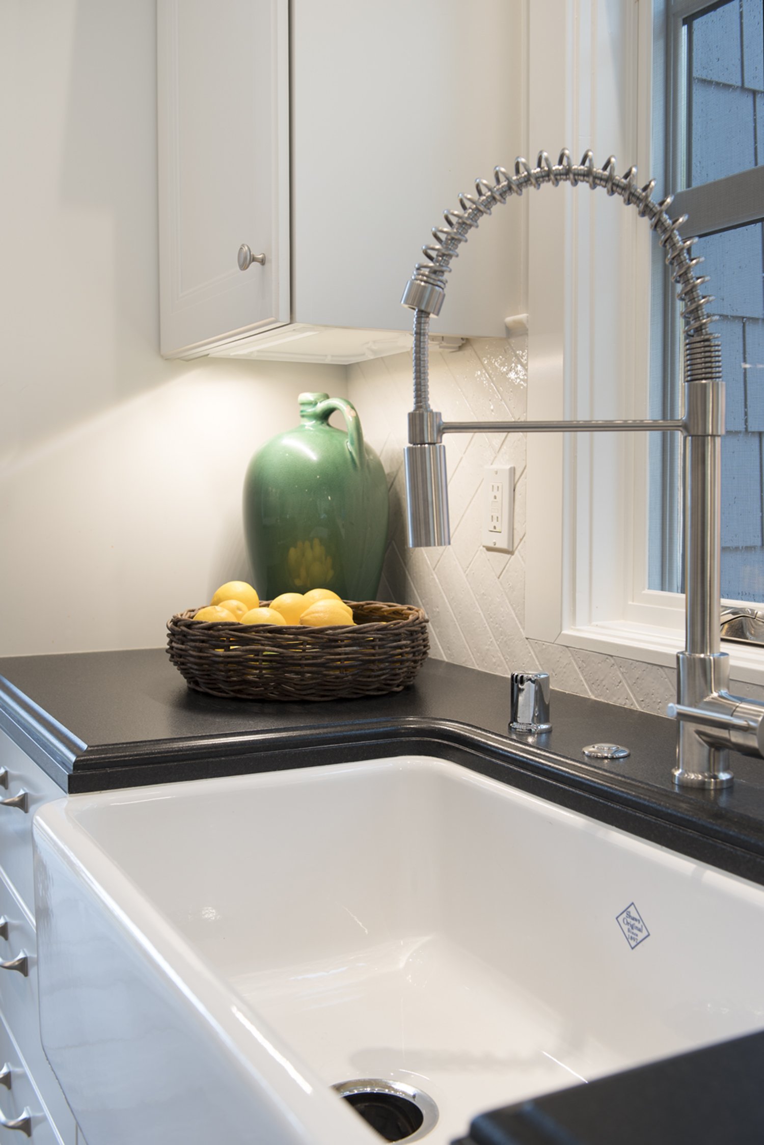  Farmhouse sink with a black countertop and silver faucet.  