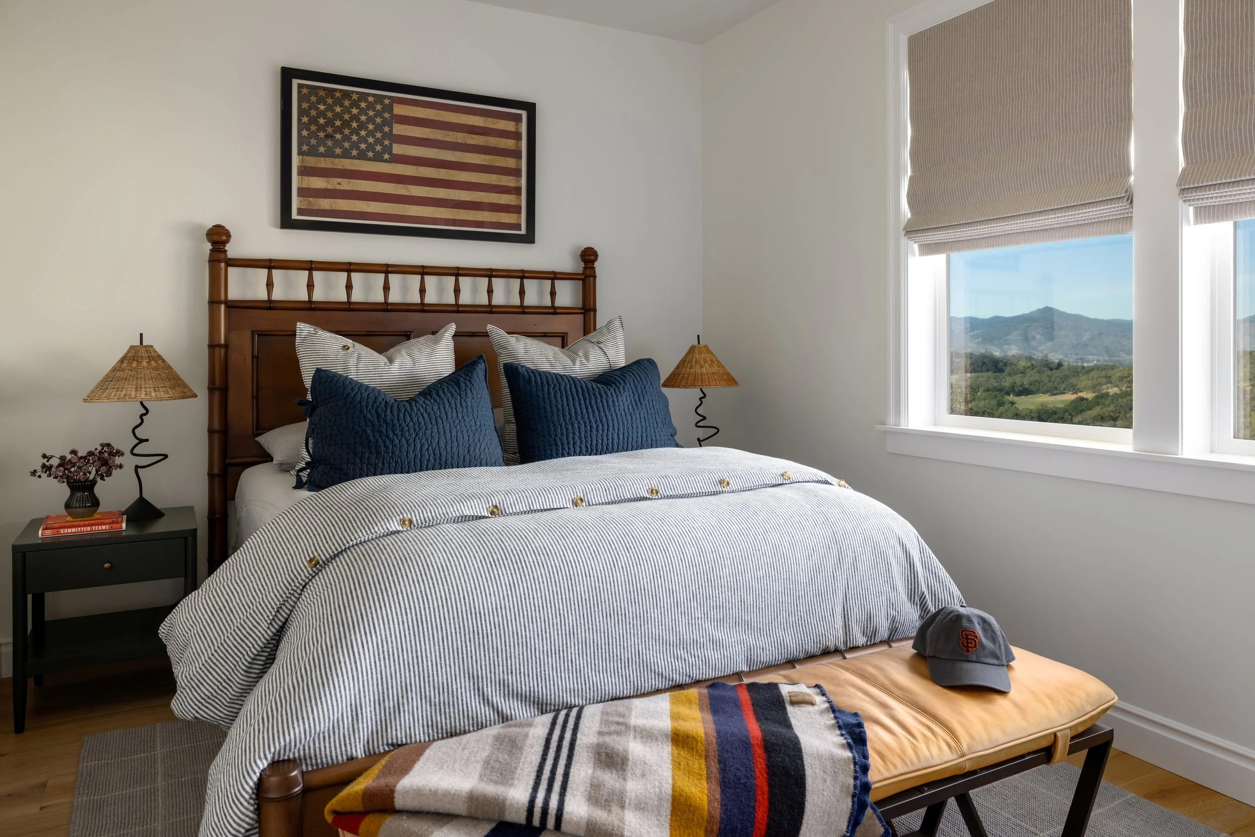 Boys bedroom with wood spindle bed, striped bedding, vintage American flag art, rattan lamps, and hillside views — Bartlett Residence by Tama Bell Design, Ukiah CA