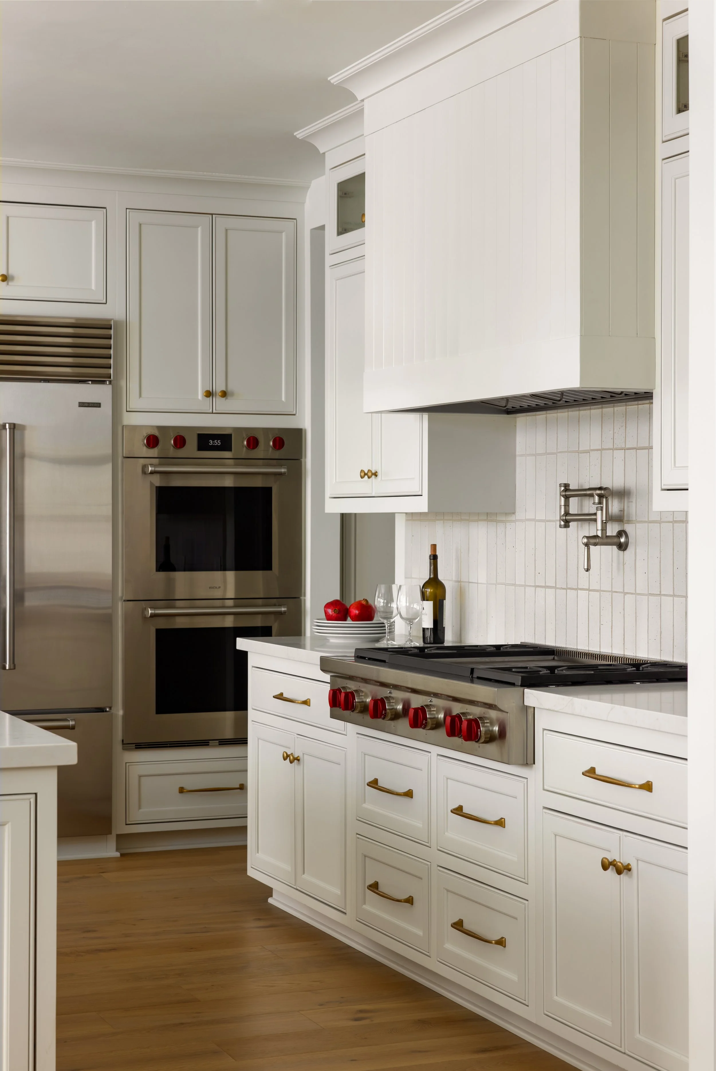 White kitchen with stainless steel double oven, brass hardware, subway tile backsplash, and professional range — Bartlett Residence by Tama Bell Design, Ukiah CA
