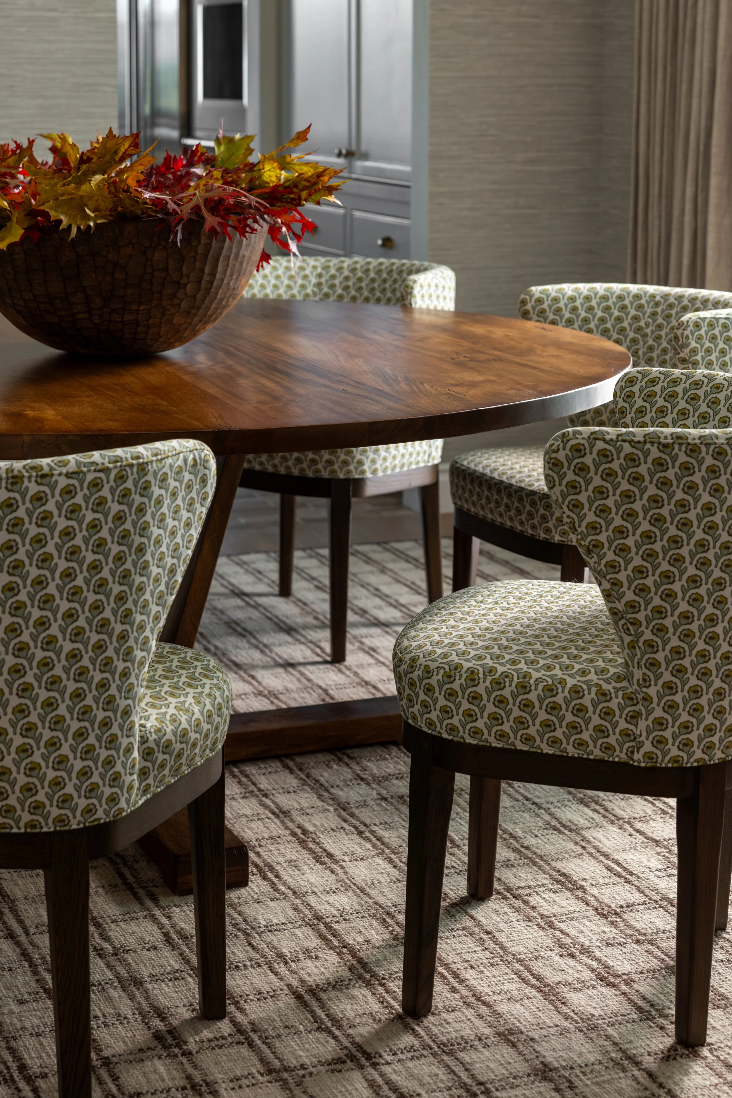 Close-up of round walnut dining table with green patterned upholstered chairs — Bartlett Residence by Tama Bell Design, Ukiah CA