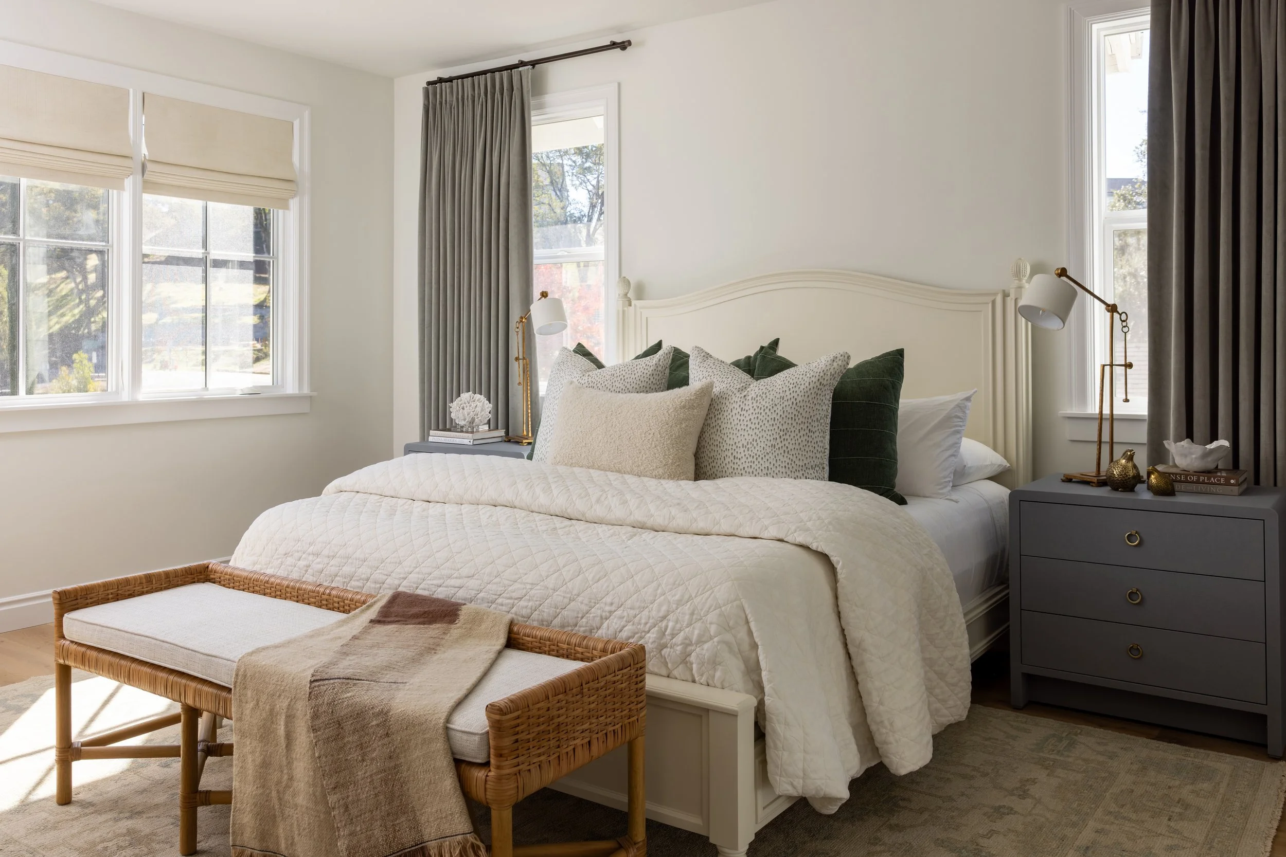 Guest bedroom with cream arched headboard, forest green velvet pillows, gray nightstands, brass lamps, and rattan bench — Bartlett Residence by Tama Bell Design, Ukiah CA