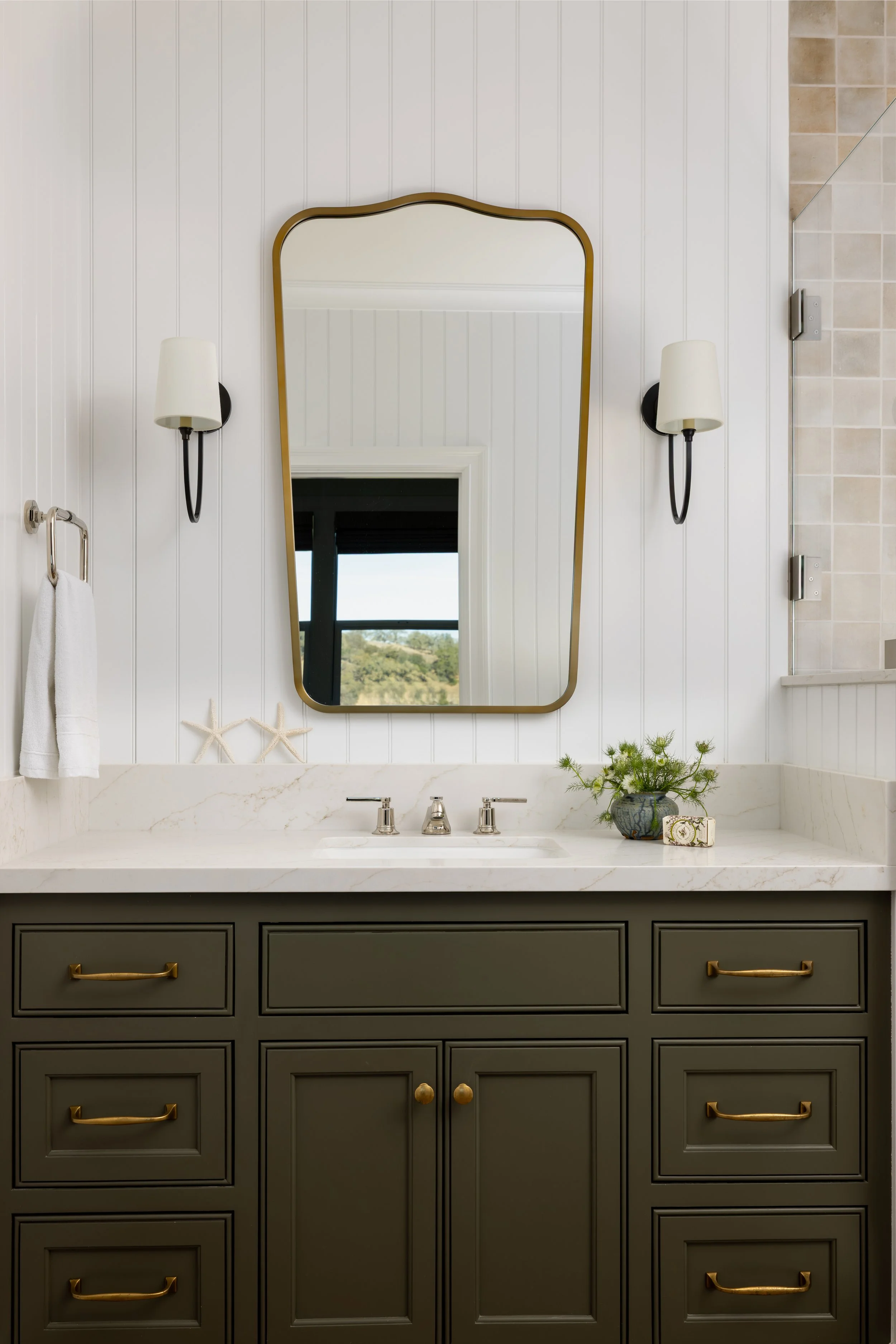 Dark olive bathroom vanity close-up with marble countertop, gold arched mirror, and black sconces — Bartlett Residence by Tama Bell Design, Ukiah CA