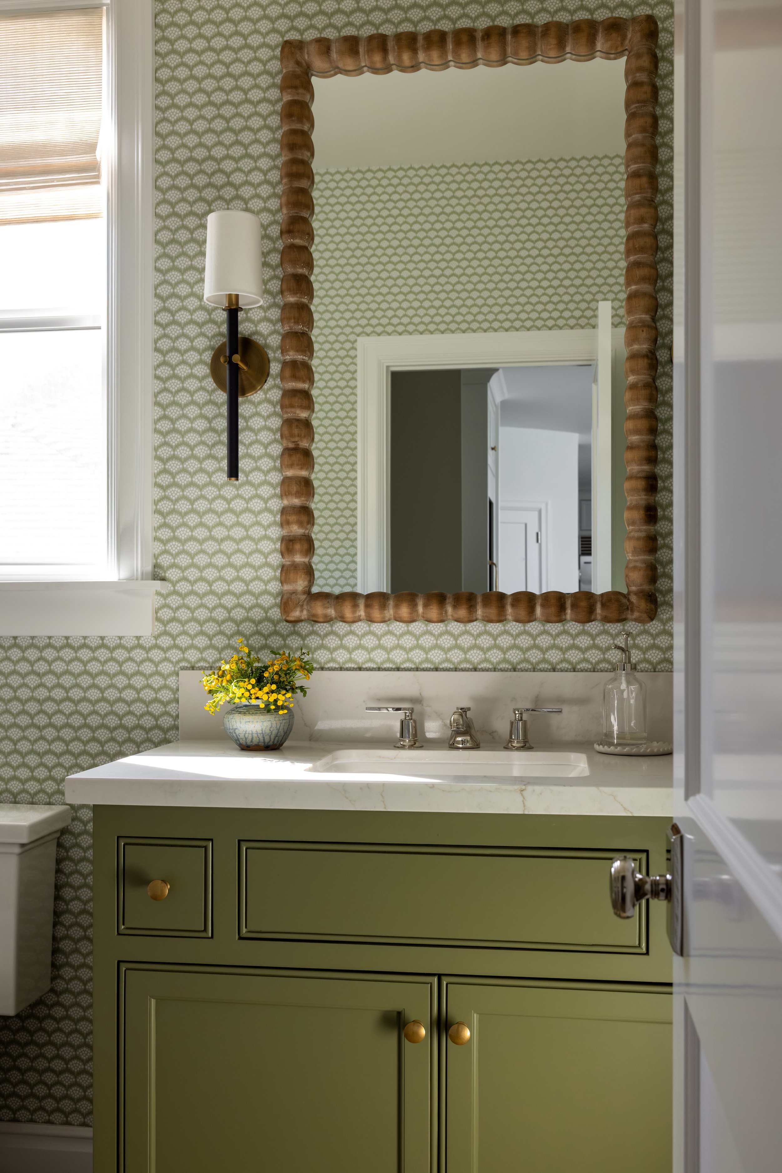 Olive green bathroom vanity with marble countertop, rattan mirror, and patterned wallpaper — Bartlett Residence by Tama Bell Design, Ukiah CA